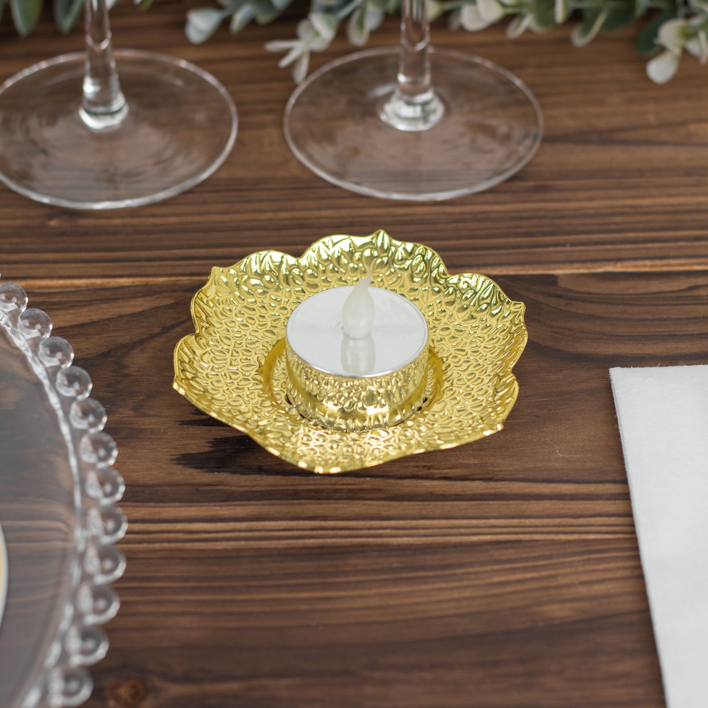 Shiny gold plum blossom tealight candle holder on a wooden table.