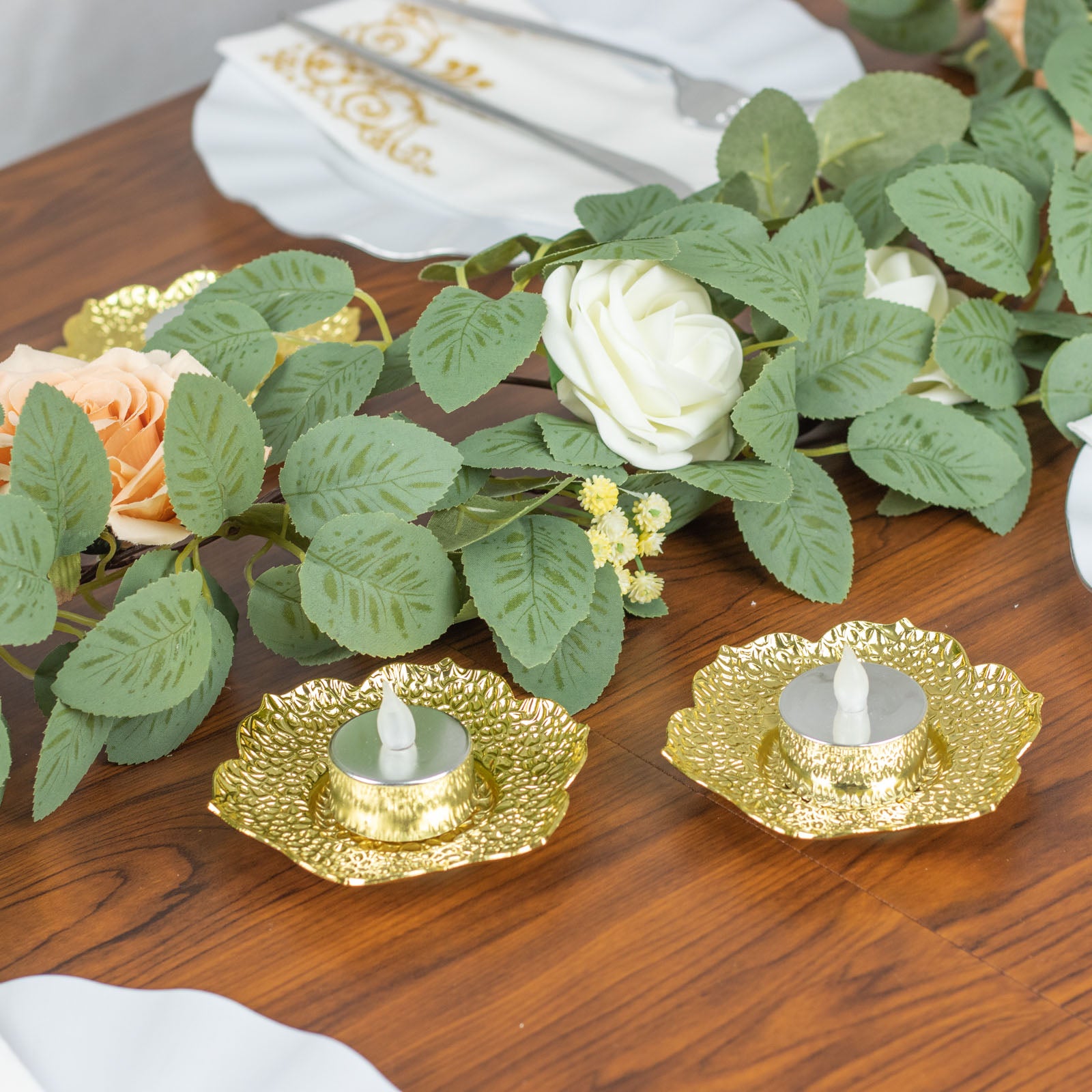 Shiny gold metal plum blossom tealight candle holders on a wooden table.