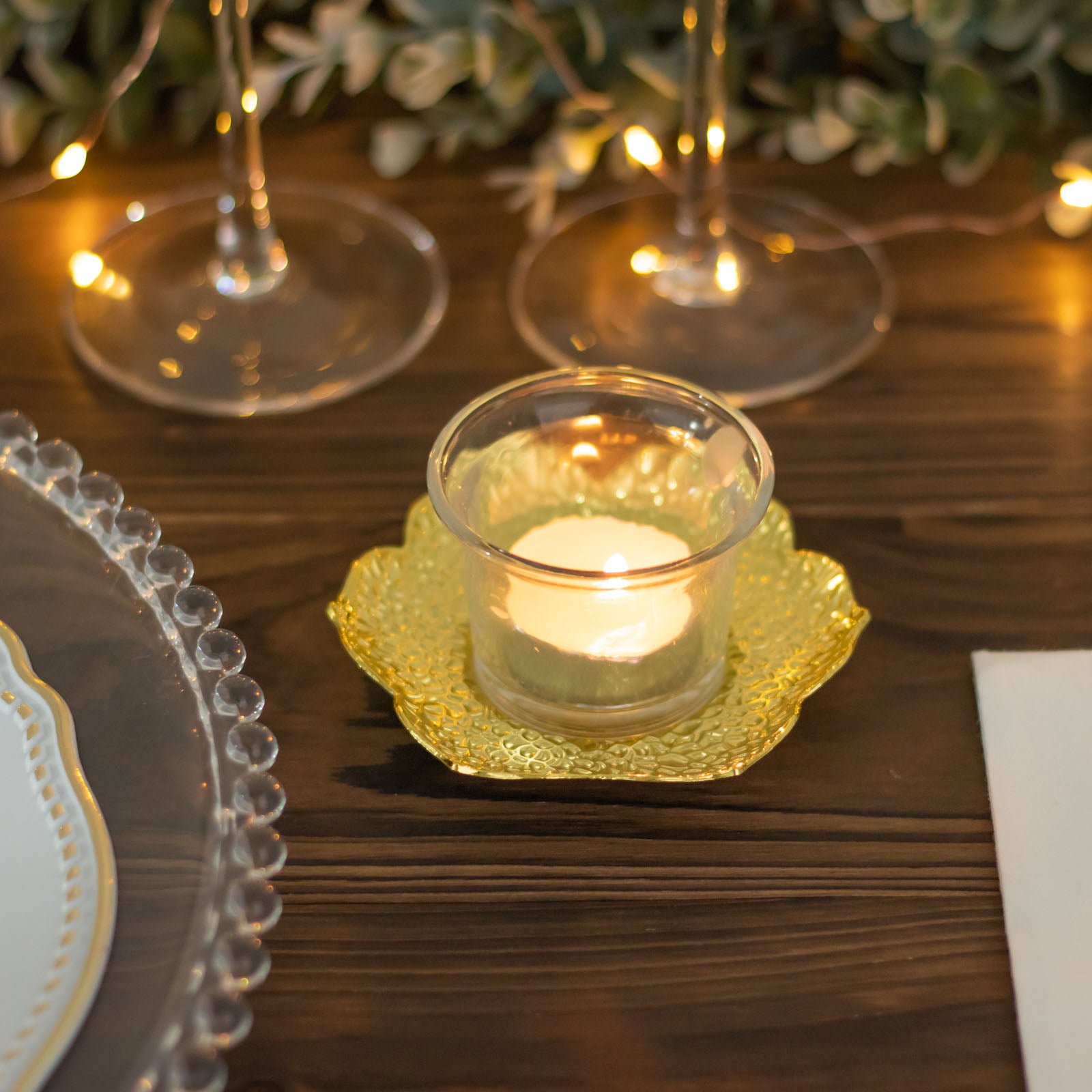 Shiny gold metal plum blossom tealight candle holder on a wooden table.