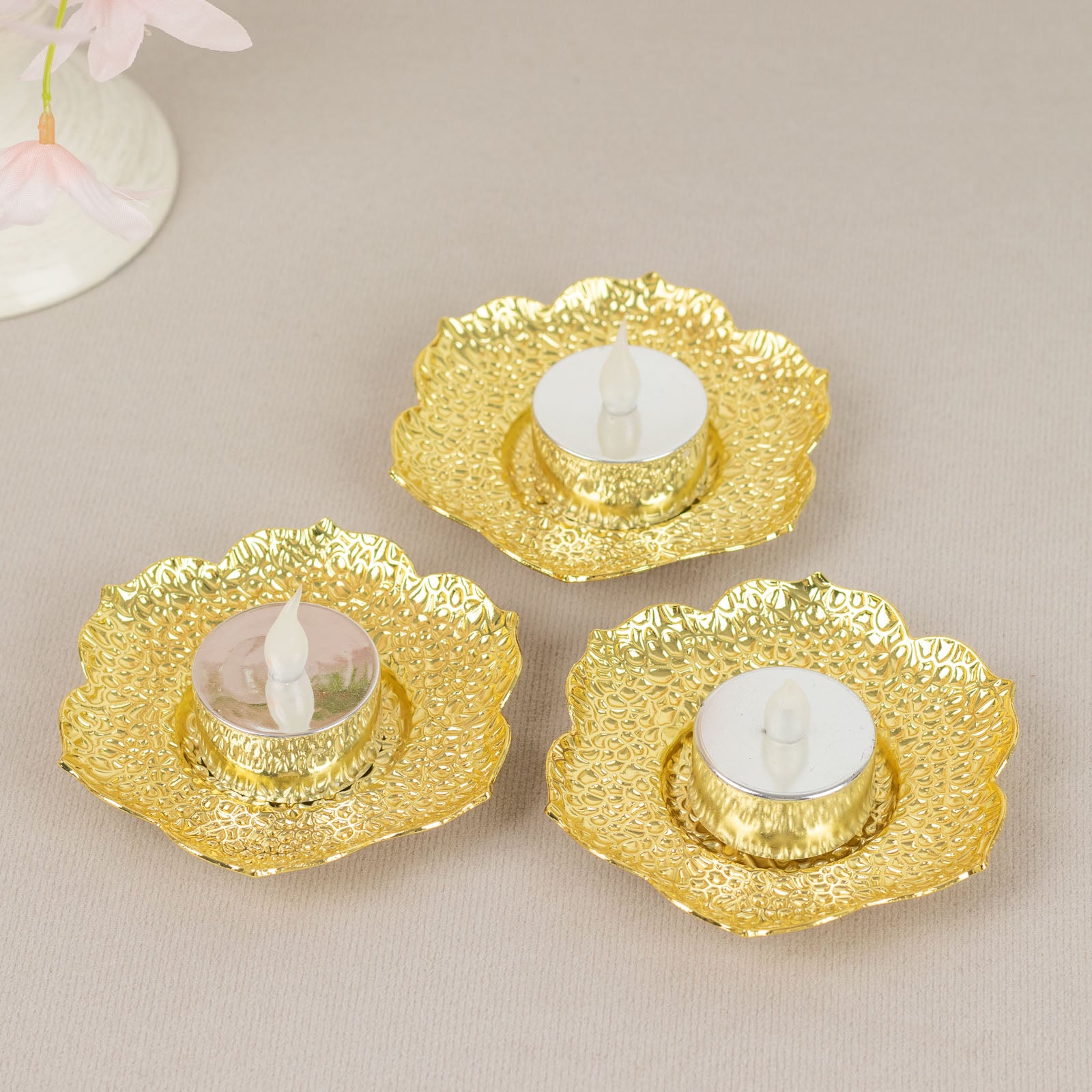 Shiny gold metal plum blossom tealight candle holders with saucers.