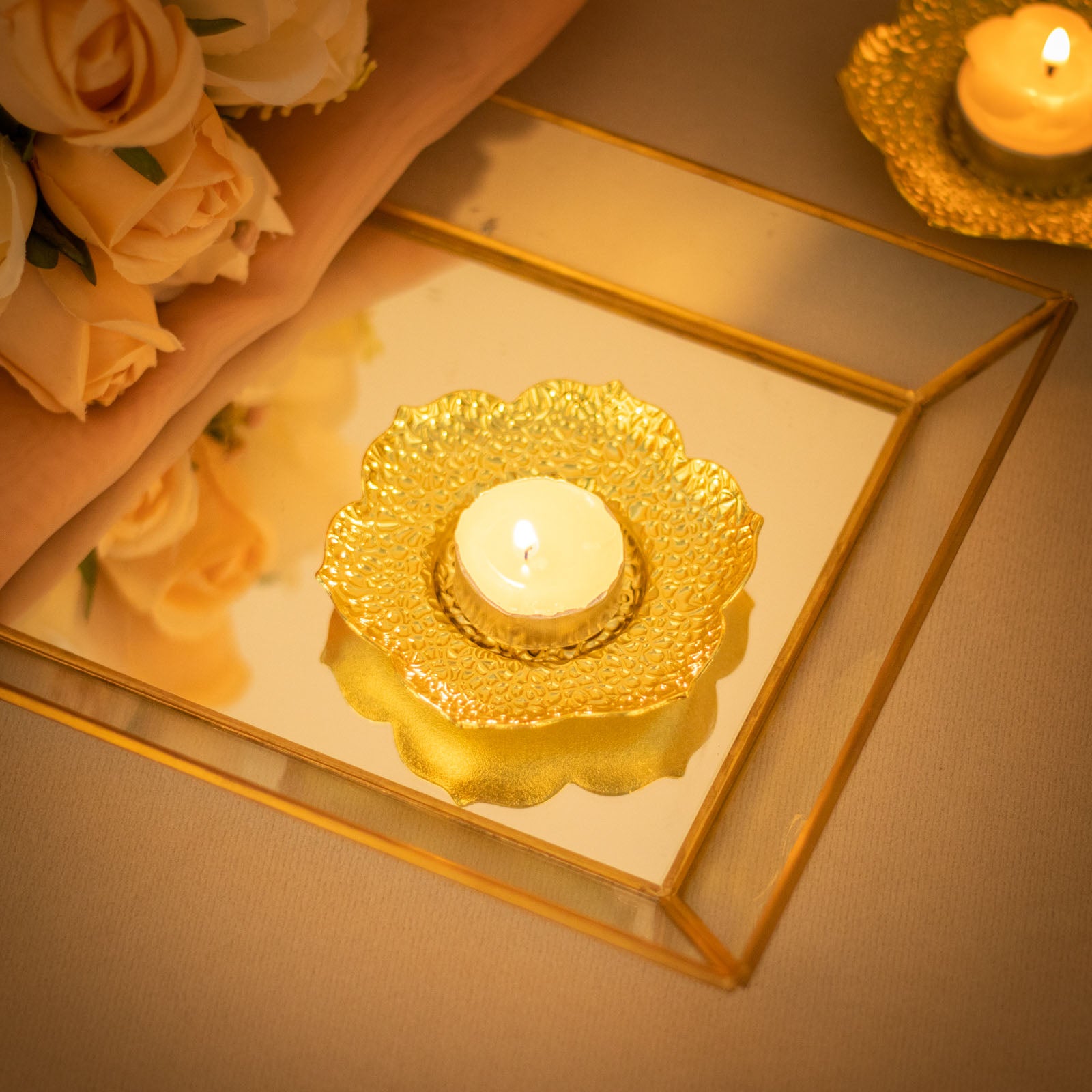 Shiny gold metal plum blossom tealight candle holder on a mirrored tray.