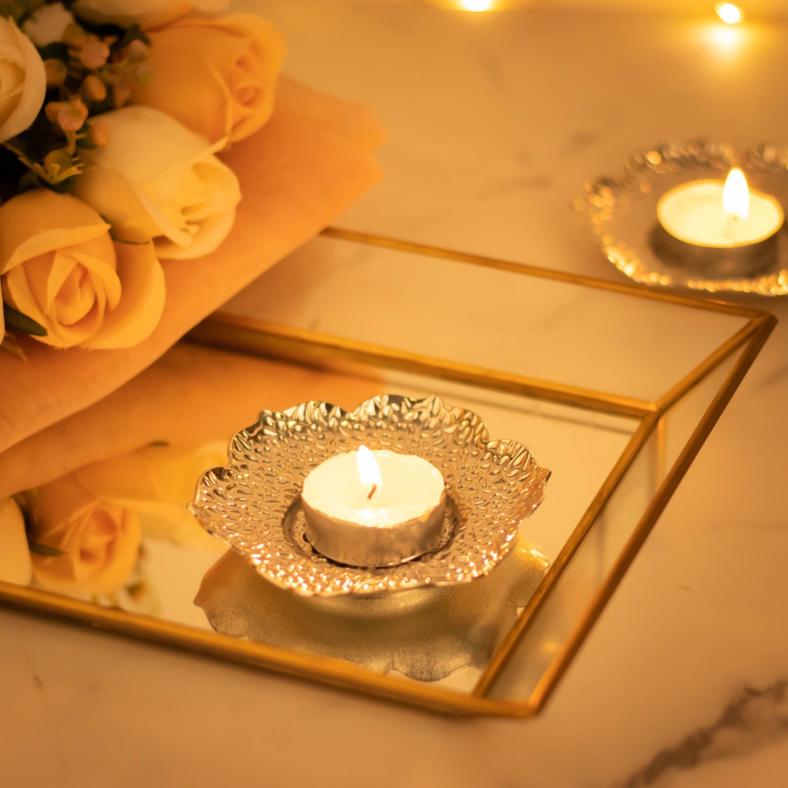 Shiny silver metal plum blossom tealight candle holders on a decorative tray.