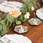 Shiny silver plum blossom tealight candle holders on a table setting.
