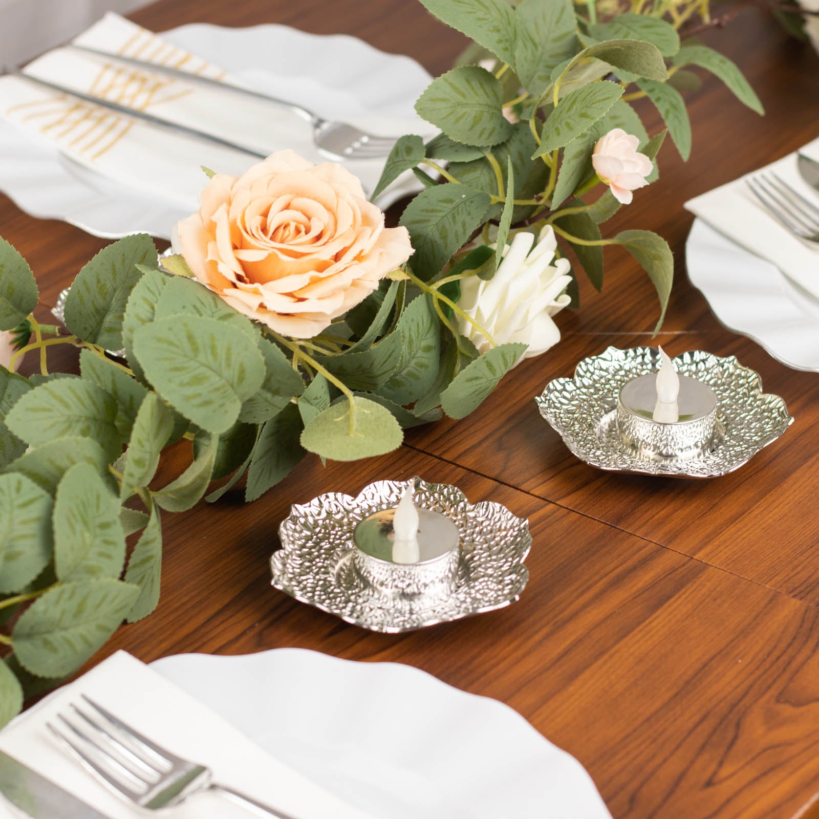 Shiny silver plum blossom tealight candle holders on a table setting.
