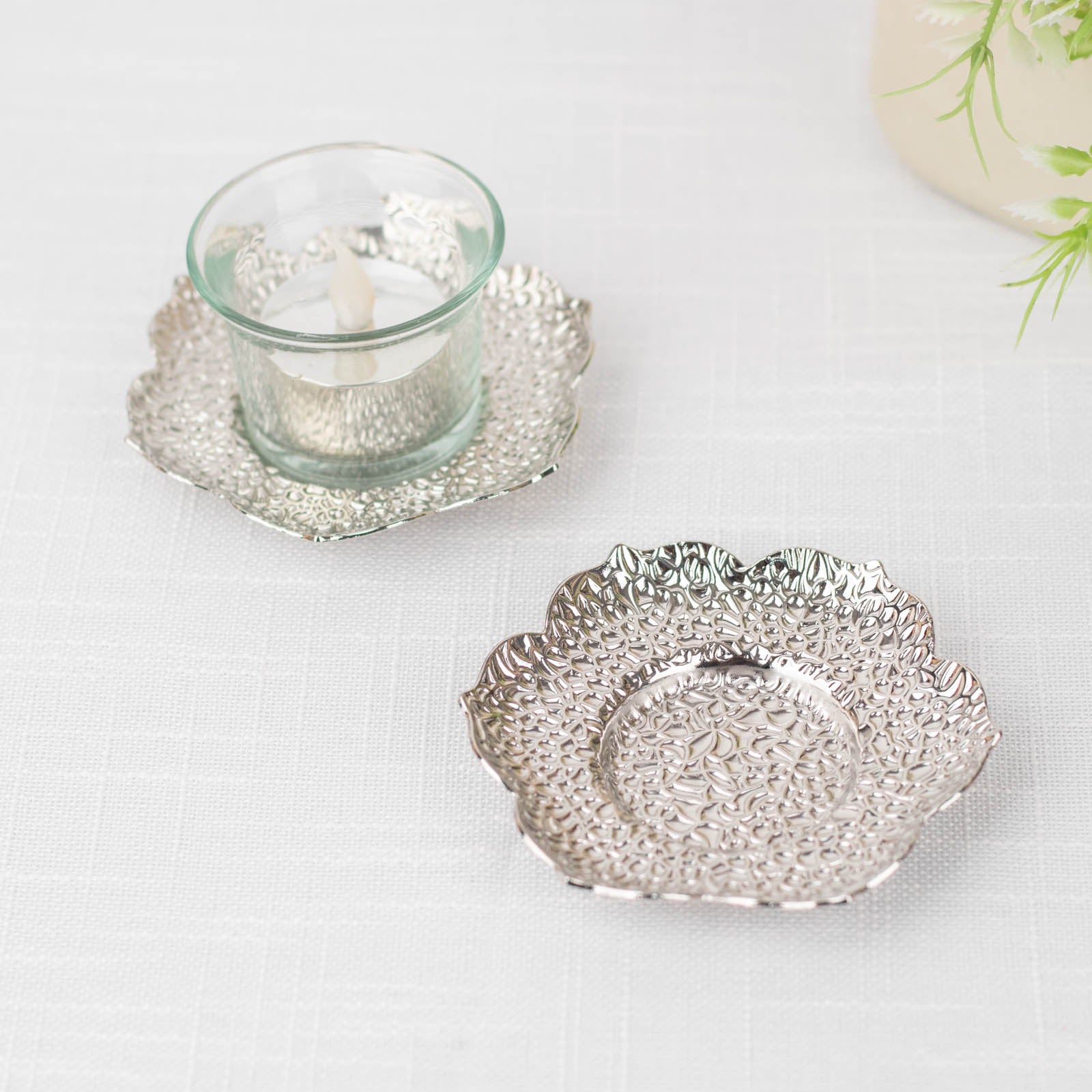 Shiny silver metal plum blossom tealight candle holders and saucers.