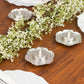 Shiny silver metal plum blossom tealight candle holders on a wooden table.