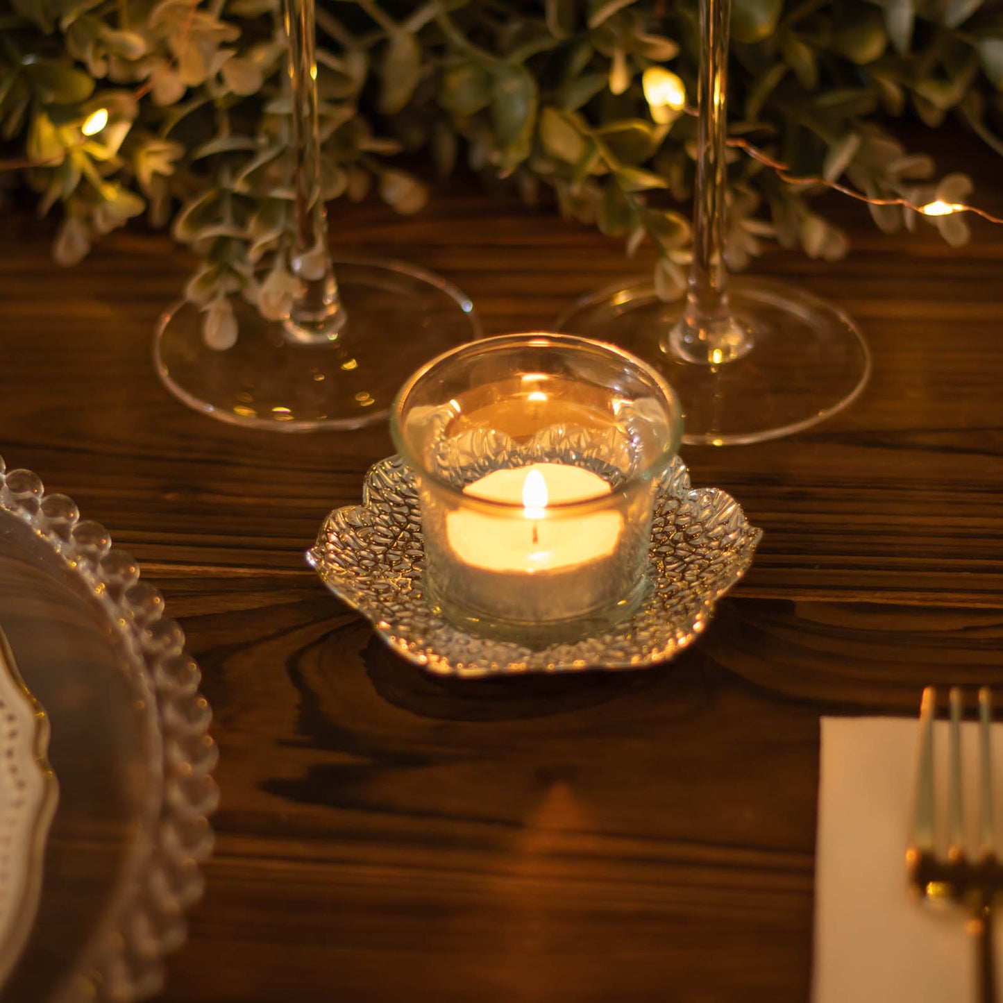 Shiny silver metal plum blossom tealight candle holder on a table setting.