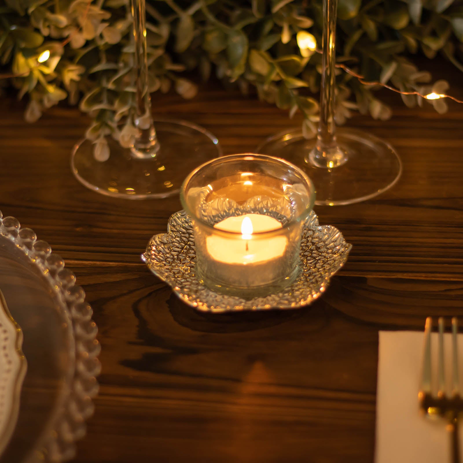 Shiny silver metal plum blossom tealight candle holder on a table setting.