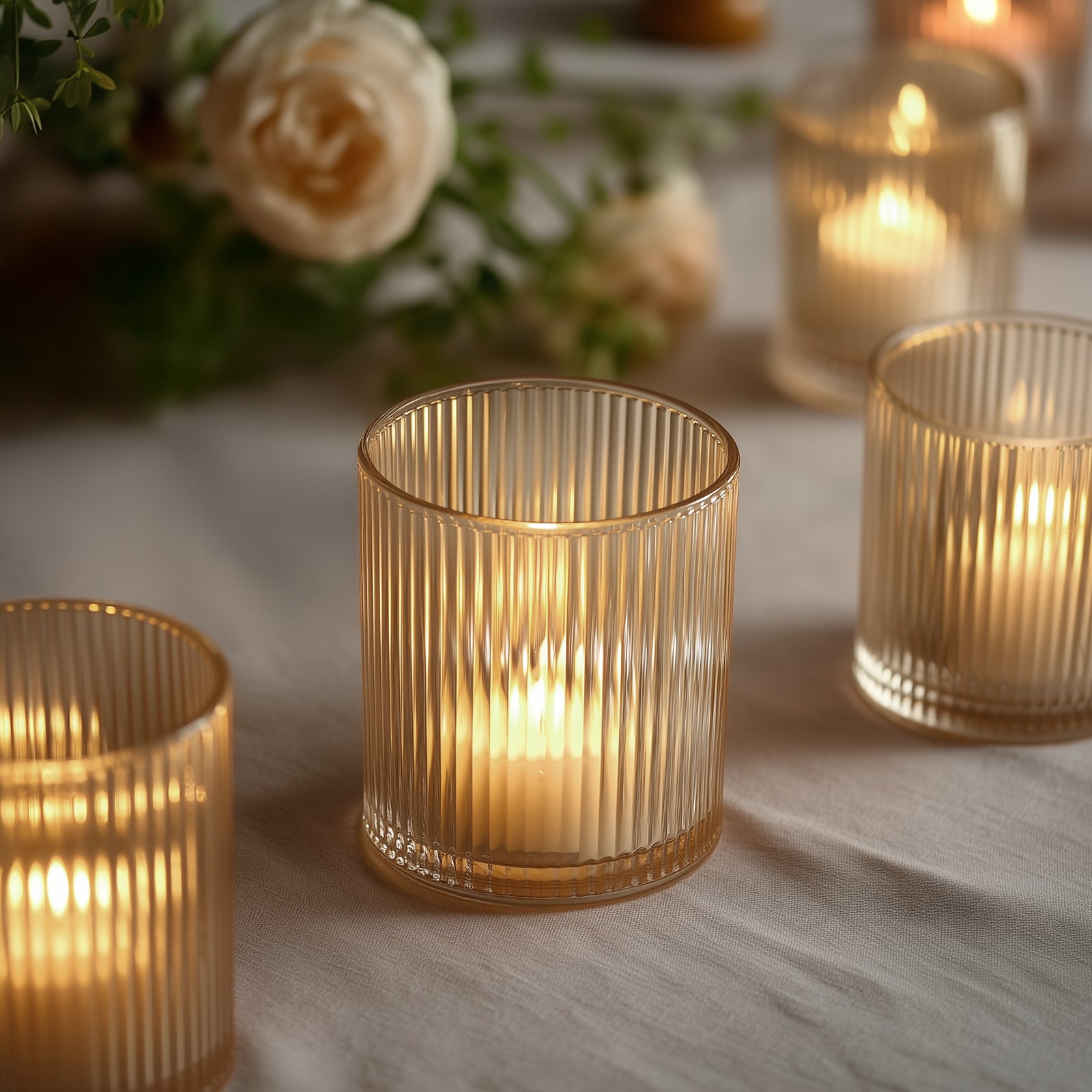 Amber gold ribbed glass votive candle holders with warm candlelight.