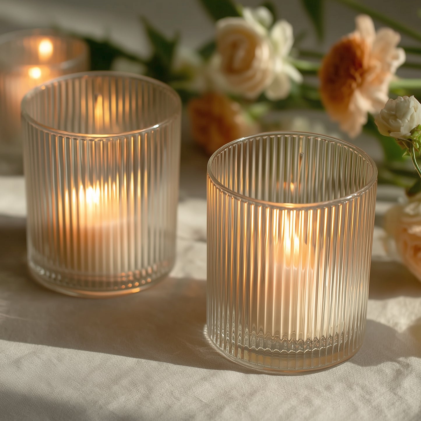 Clear ribbed glass votive candle holders with warm candlelight.
