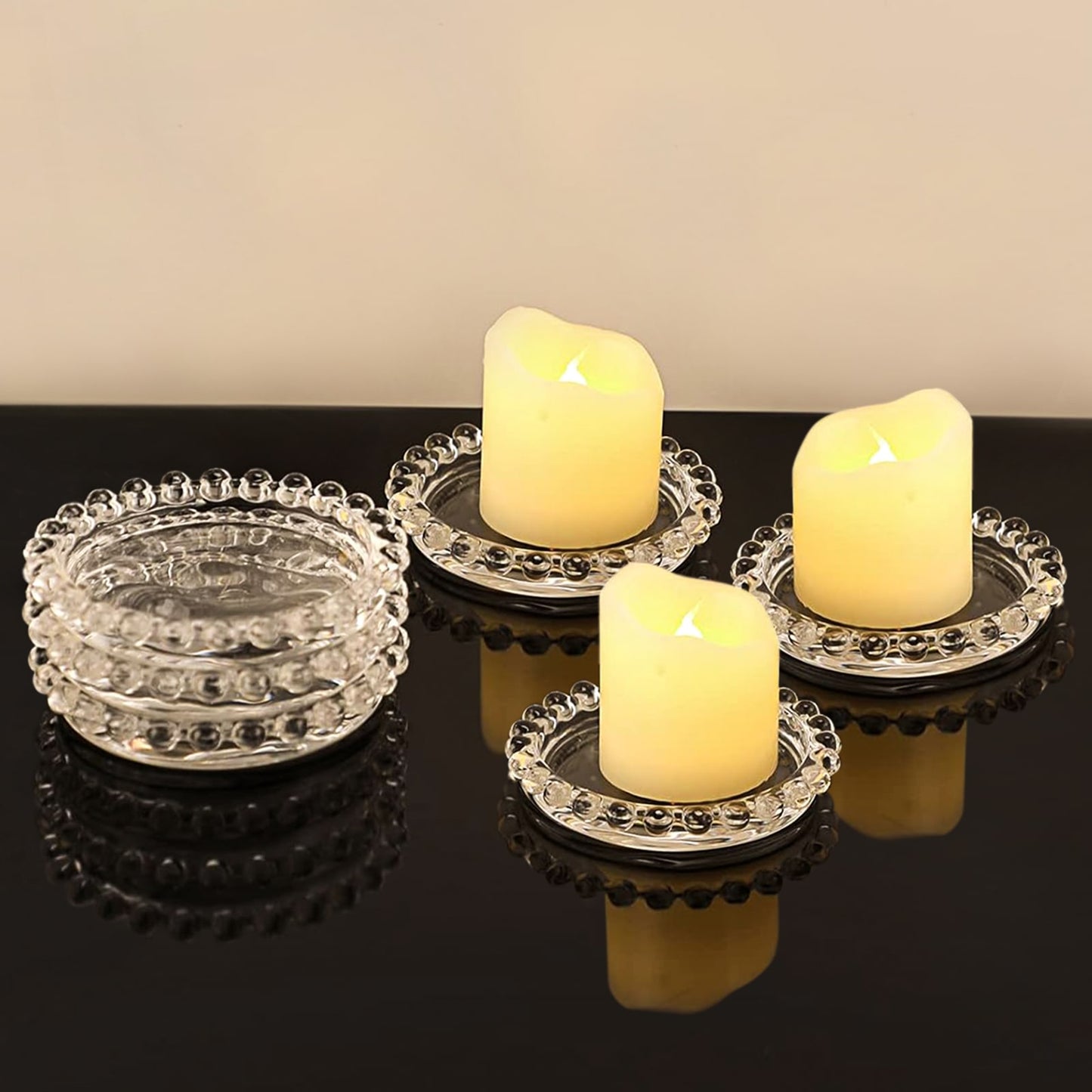 Clear glass pillar candle holder trays with beaded rims and candles.