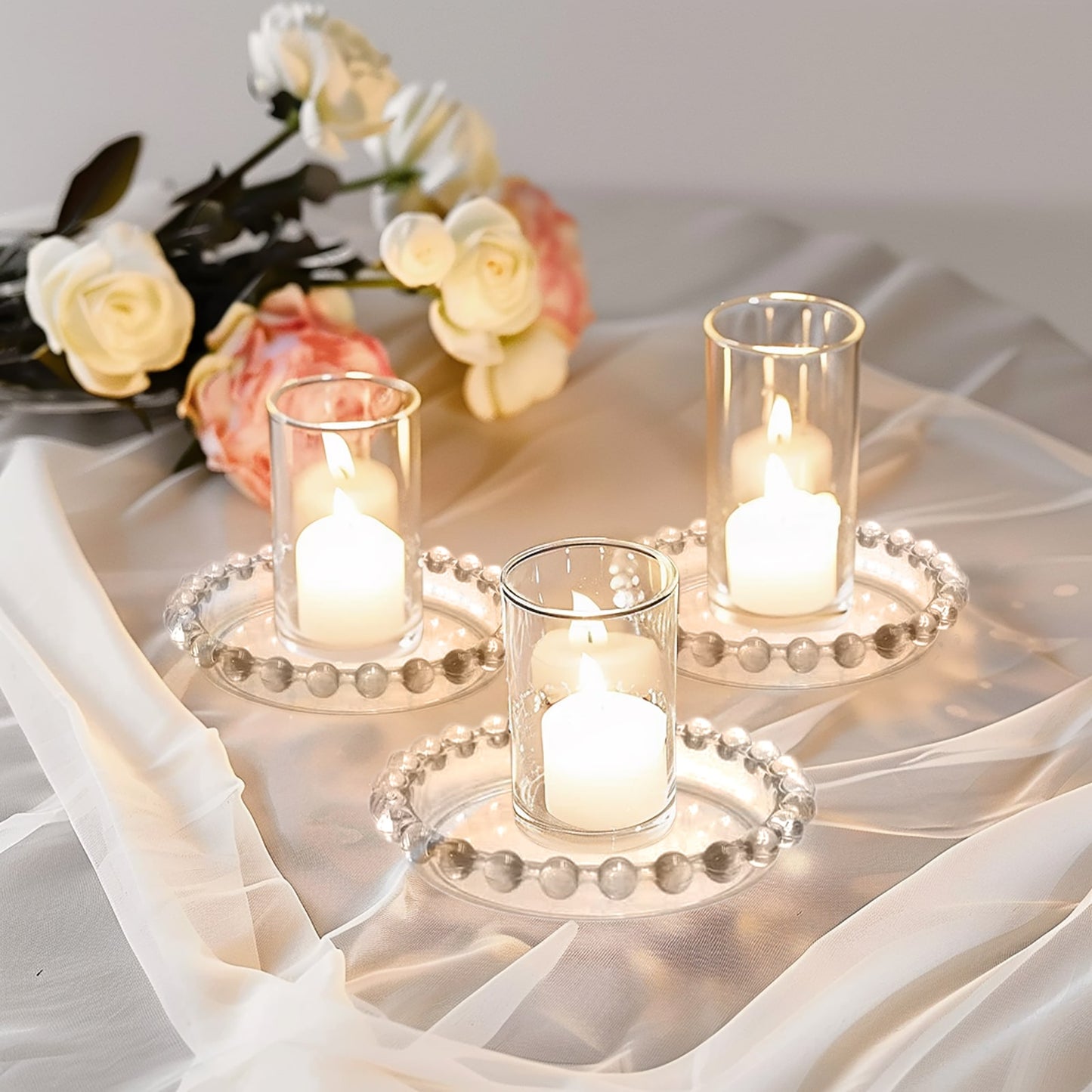 Clear glass candle holder trays with beaded rims and candles.