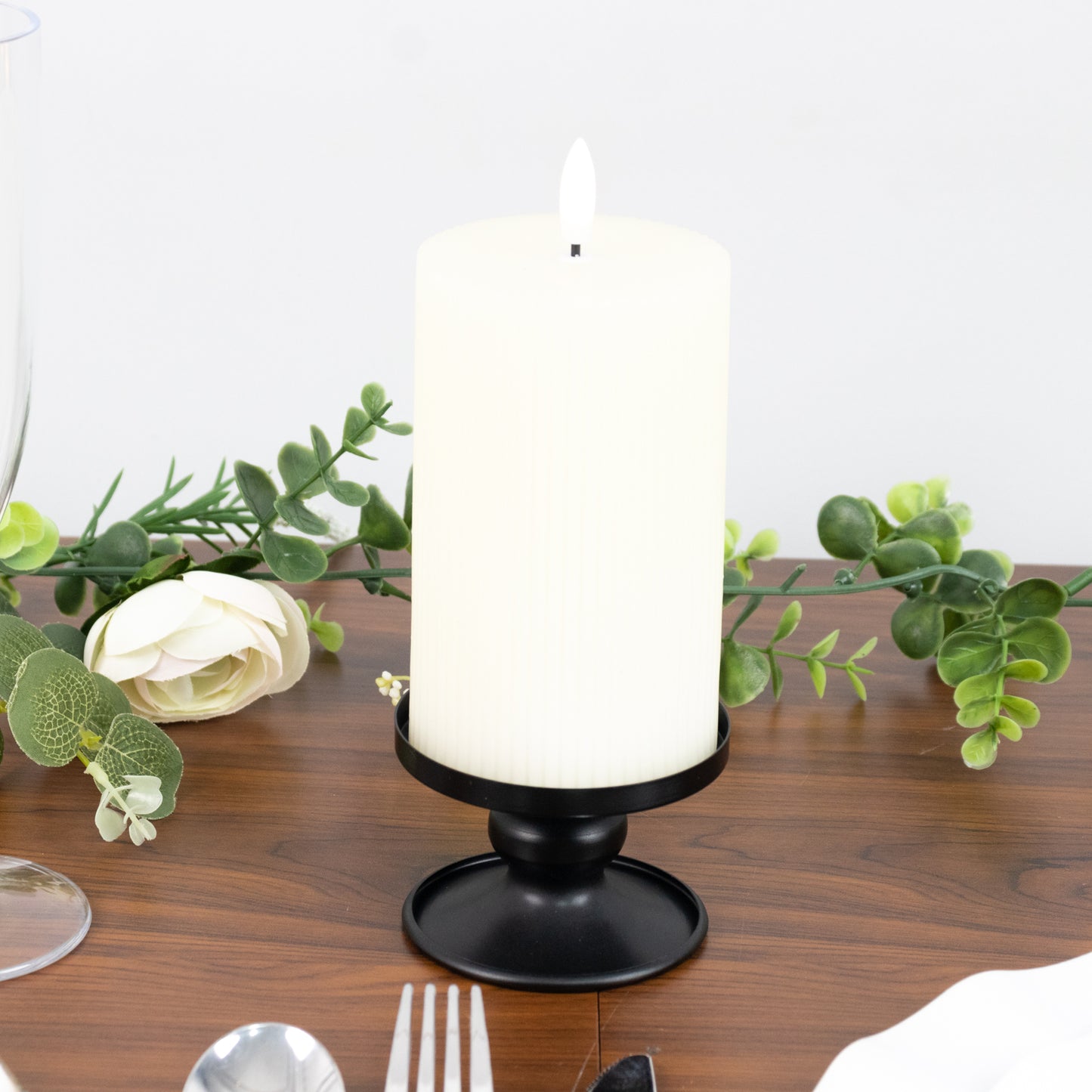 Black metal candle holder with white pillar candle, perfect for elegant decor.