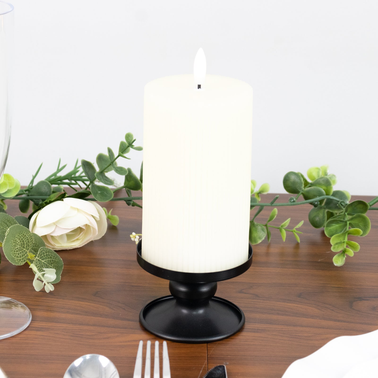Black metal candle holder with white pillar candle, perfect for elegant decor.