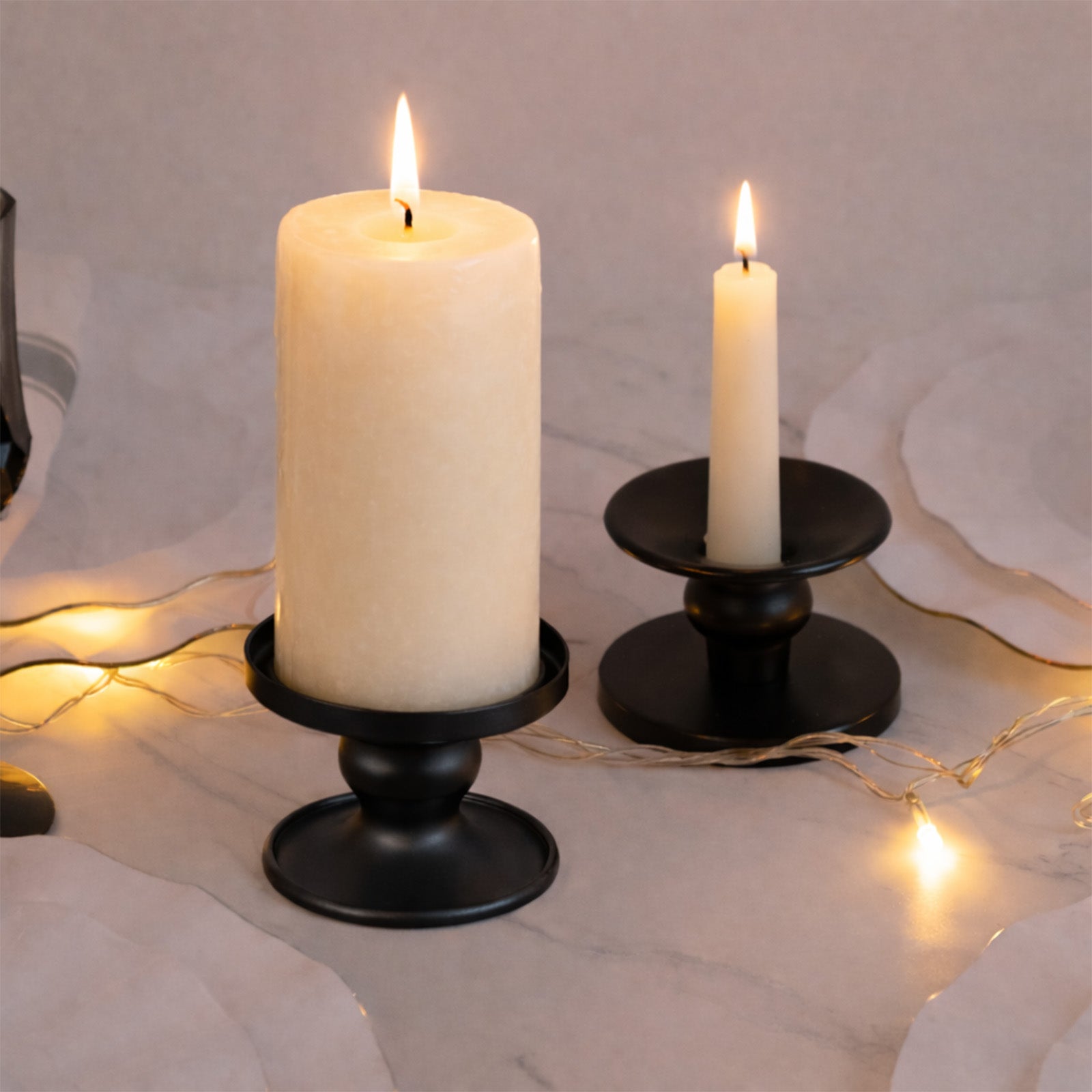Black metal candle holders in a decorative display with lit candles.