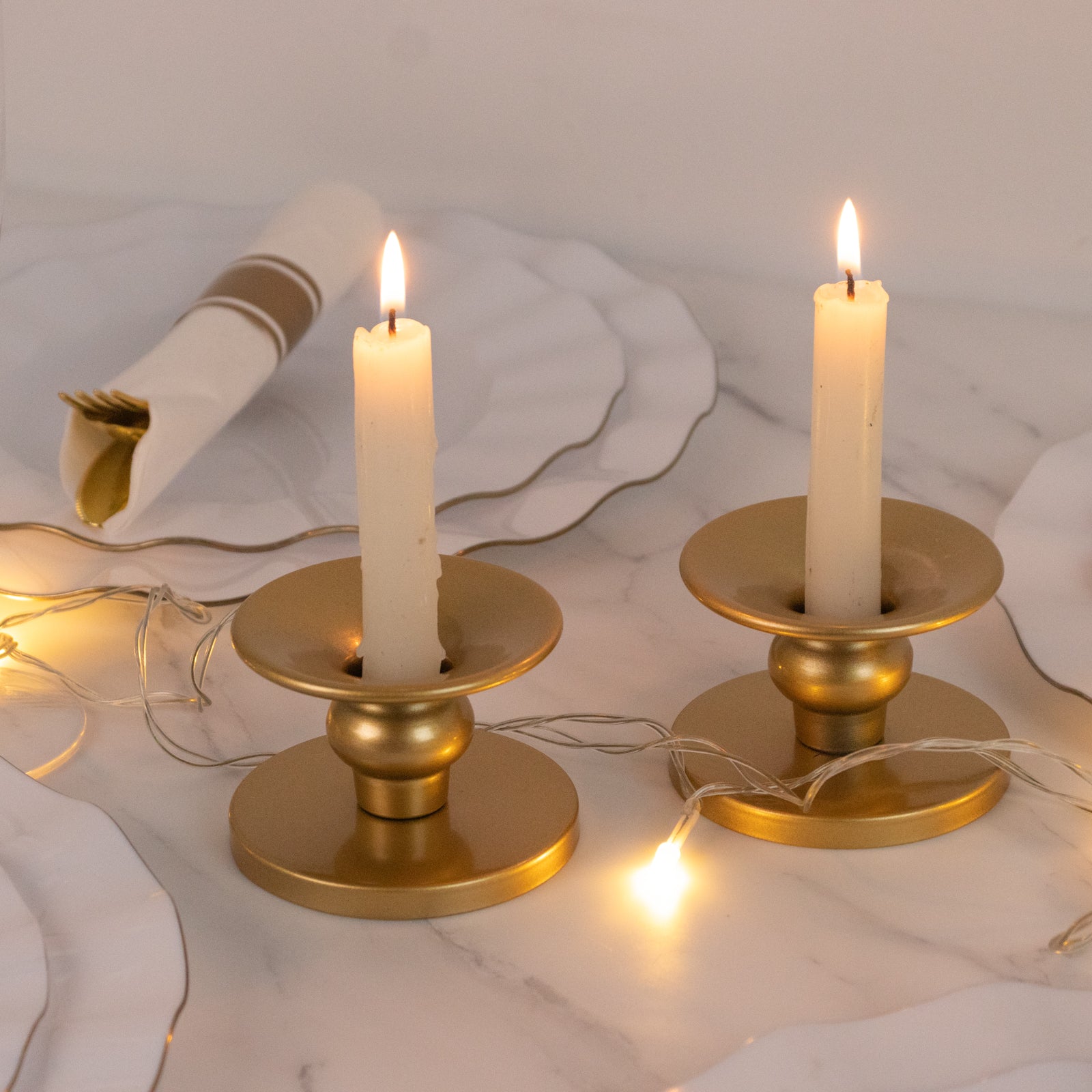 Gold metal candle holders with taper candles, perfect for elegant decor.