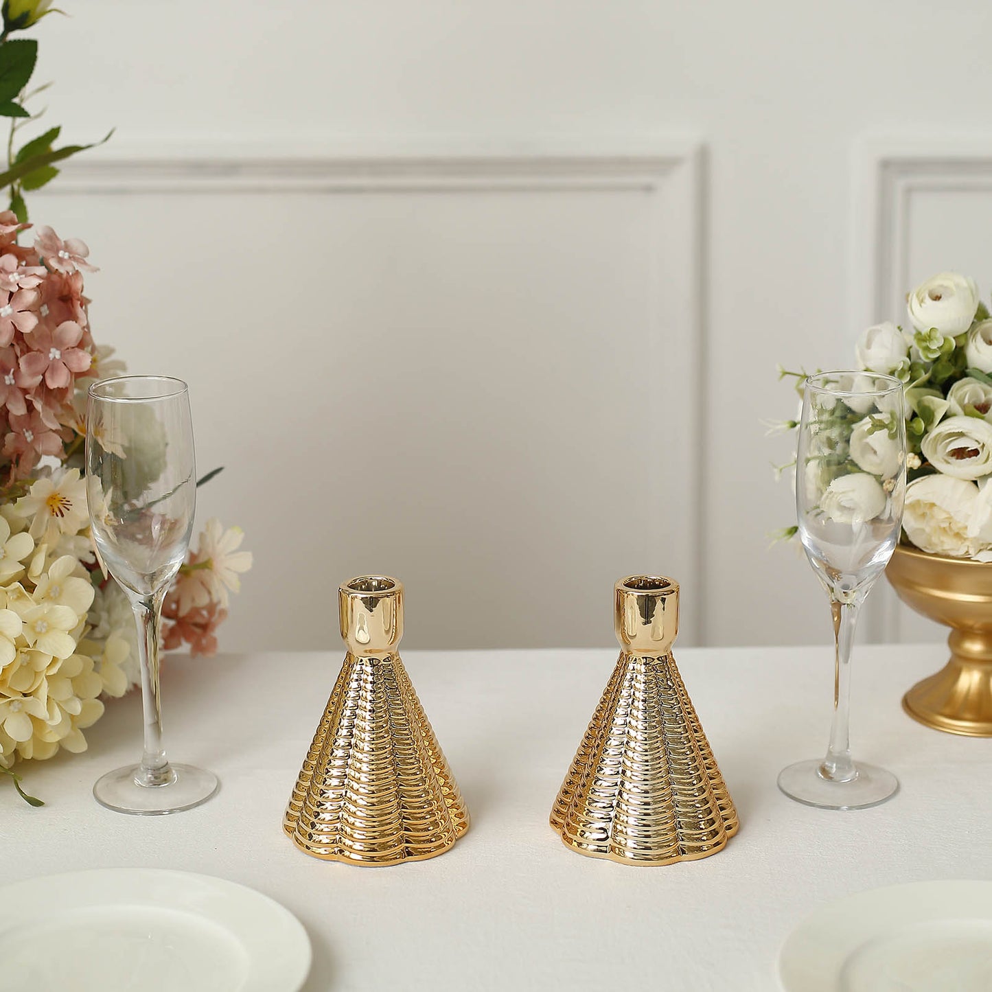 Metallic gold ribbed ceramic taper candle holders, cone shaped, on a table setting.