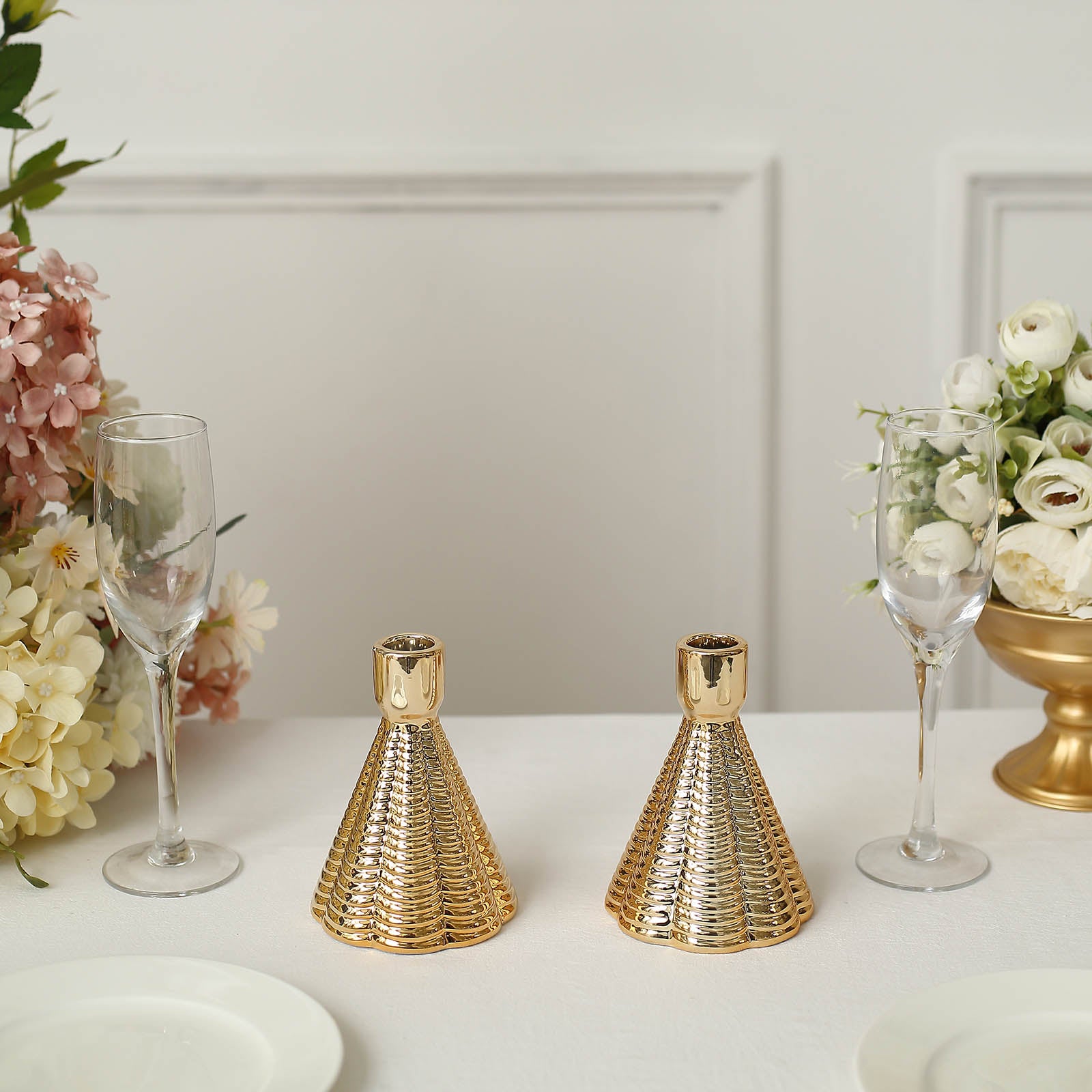 Metallic gold ribbed ceramic taper candle holders, cone shaped, on a table setting.