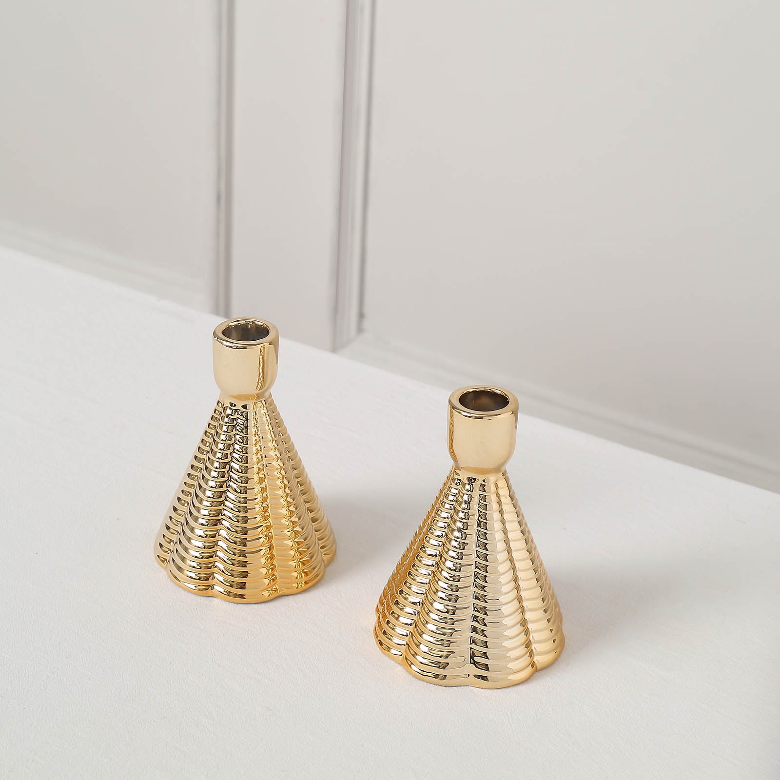 Metallic gold ribbed ceramic taper candle holders, cone shaped.