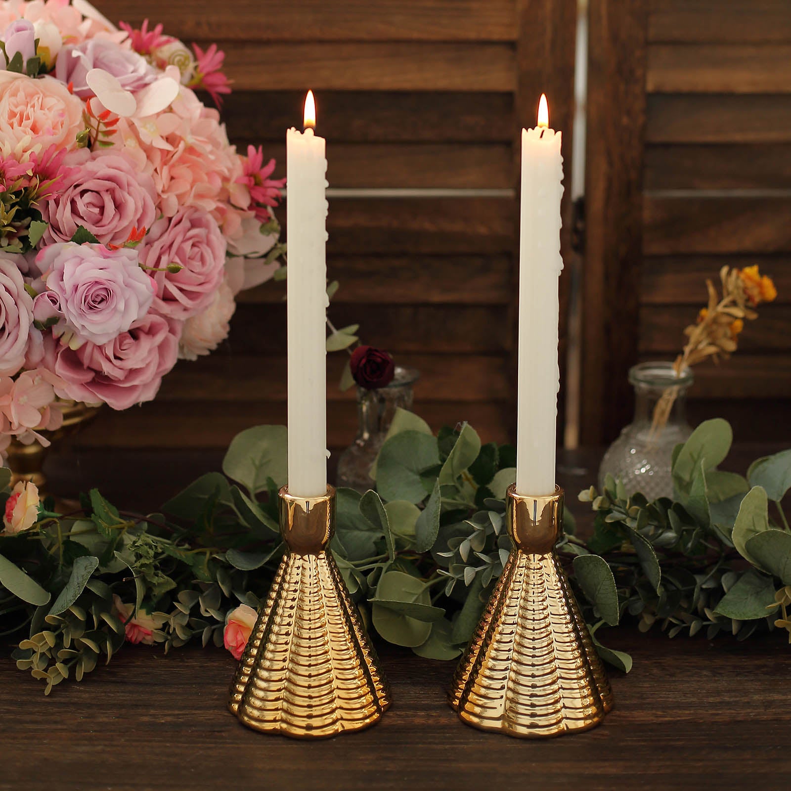 Metallic gold ribbed ceramic taper candle holders in a cone shape with white candles.