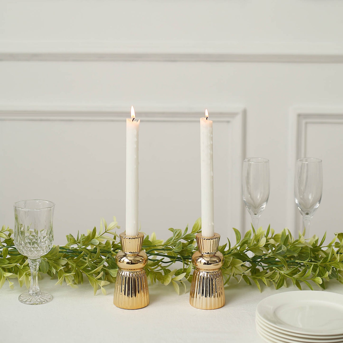Metallic gold fluted ball neck ceramic taper candle holders with white candles.