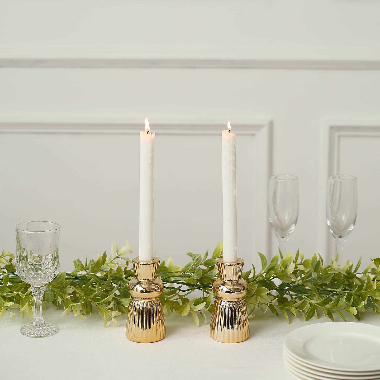 Metallic gold fluted ball neck ceramic taper candle holders with white candles.