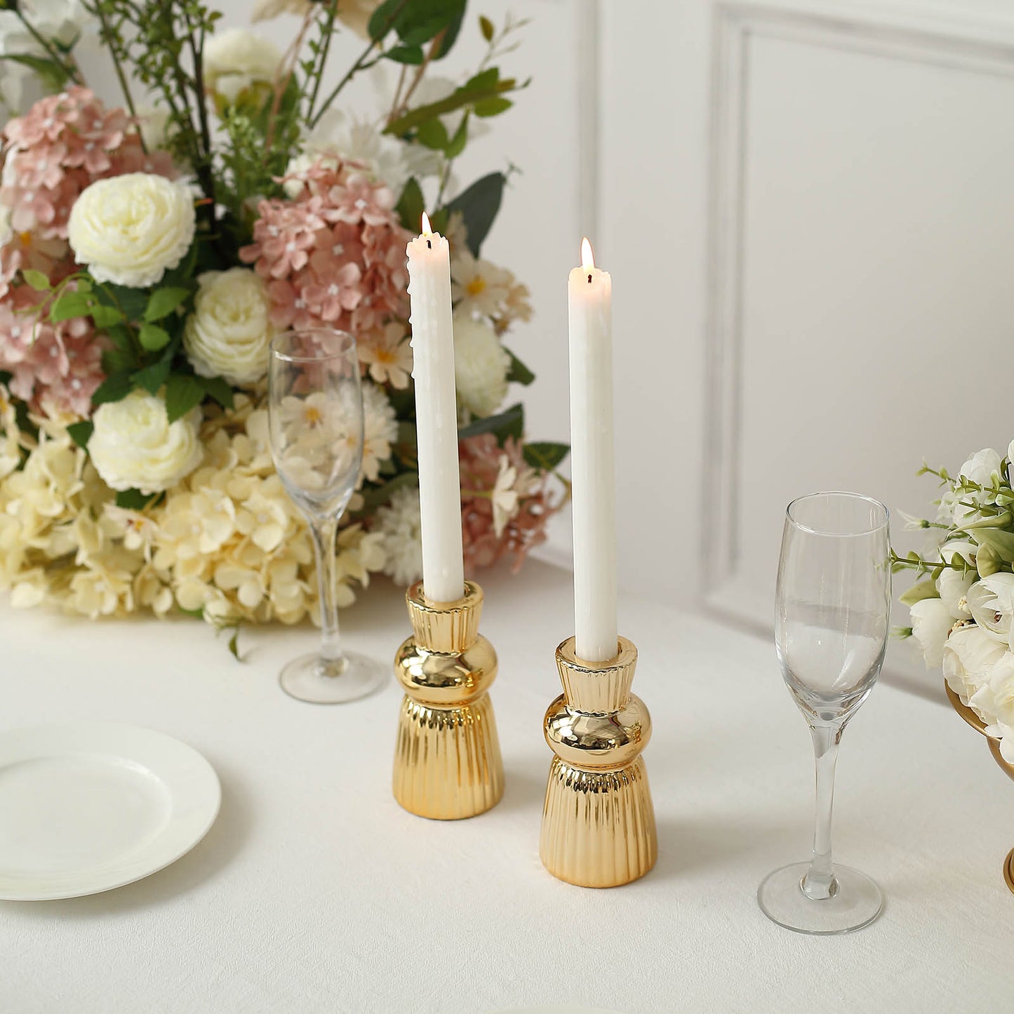 Metallic gold fluted ball neck ceramic taper candle holders with white candles.