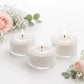 White tealight candles in clear cups, burning softly on a floral background.