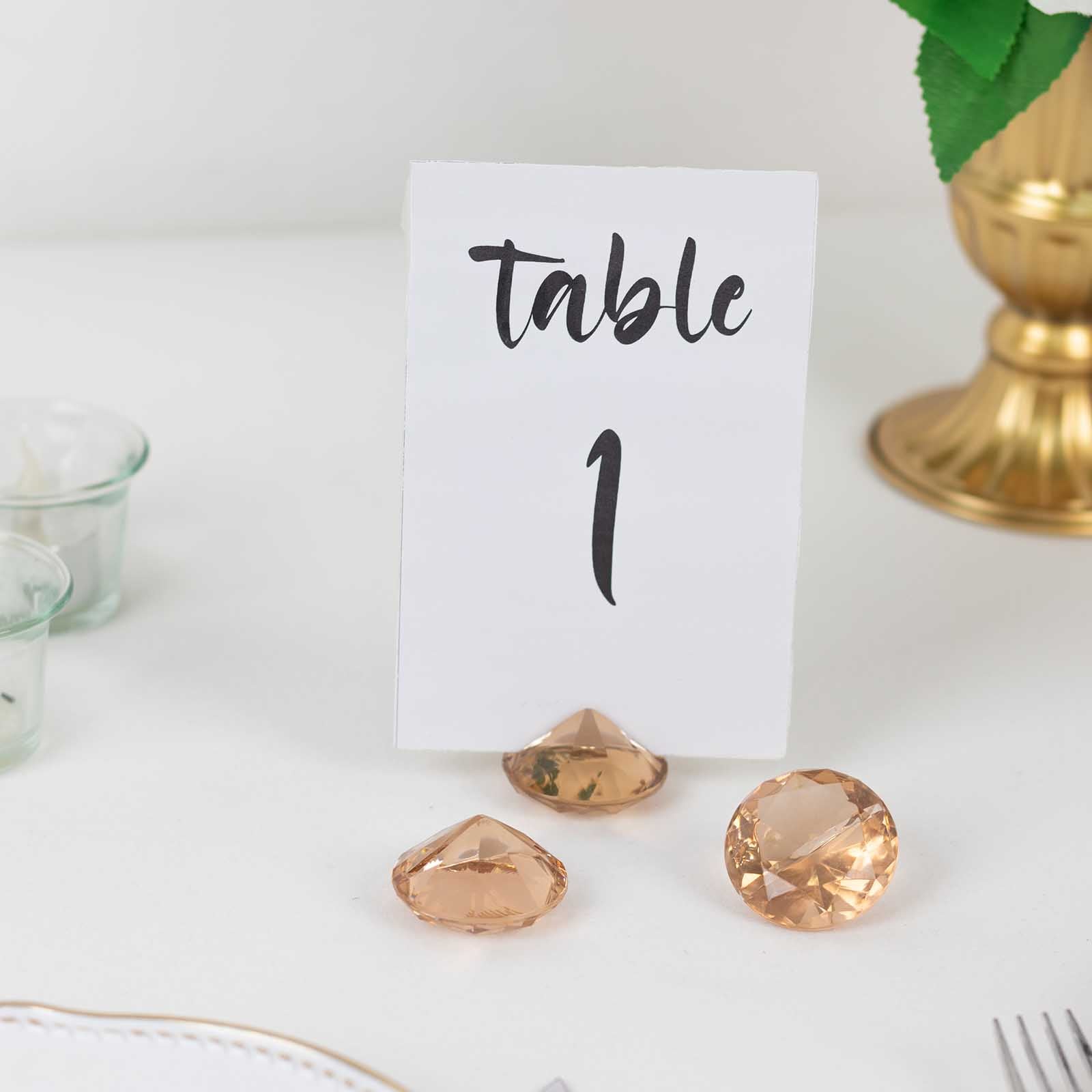 Amber diamond-shaped place card holders on a table with a sign.