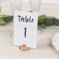 Amber diamond-shaped place card holder with table number on a wedding table.