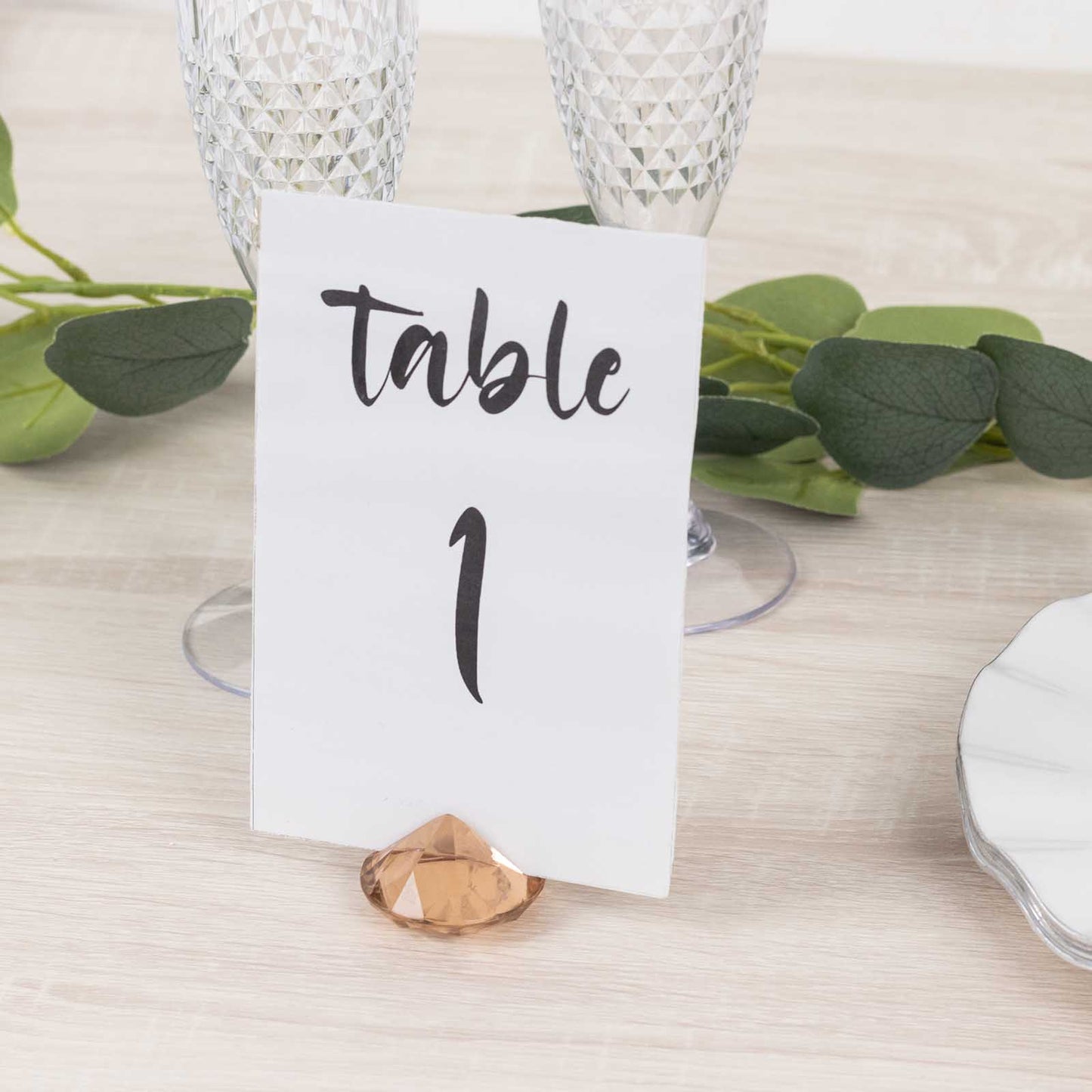 Amber diamond-shaped place card holder with table number on a wedding table.