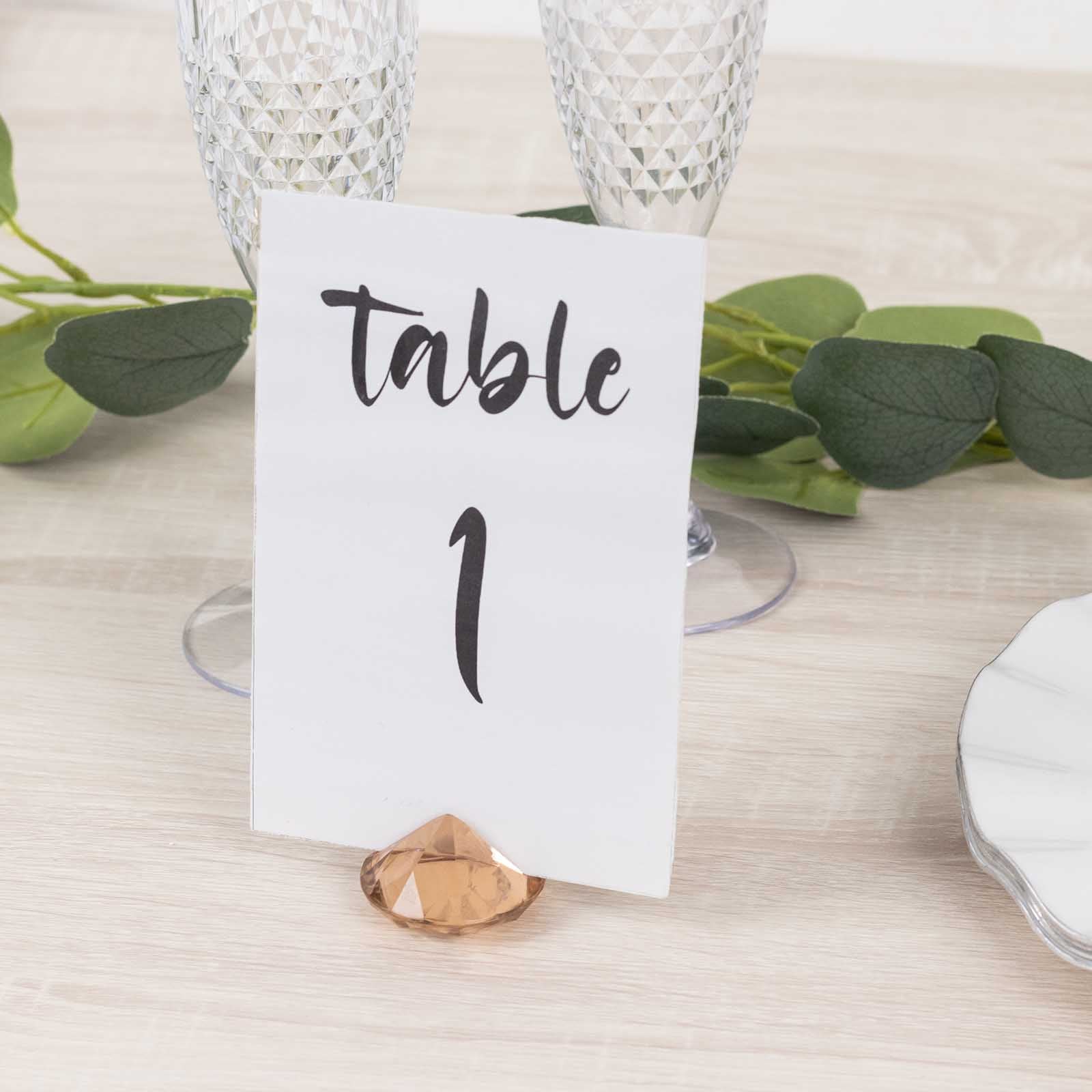 Amber diamond-shaped place card holder with table number on a wedding table.