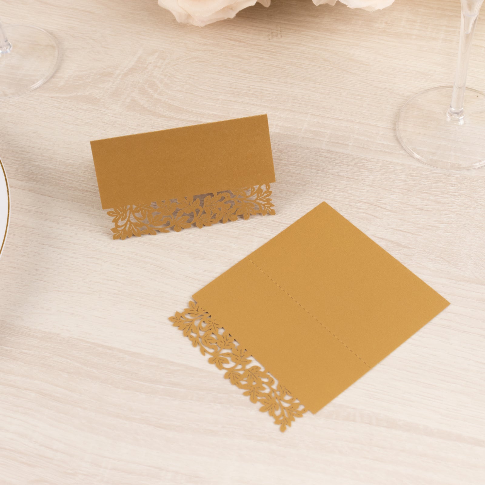 Gold wedding table number cards with laser cut leaf vine design.