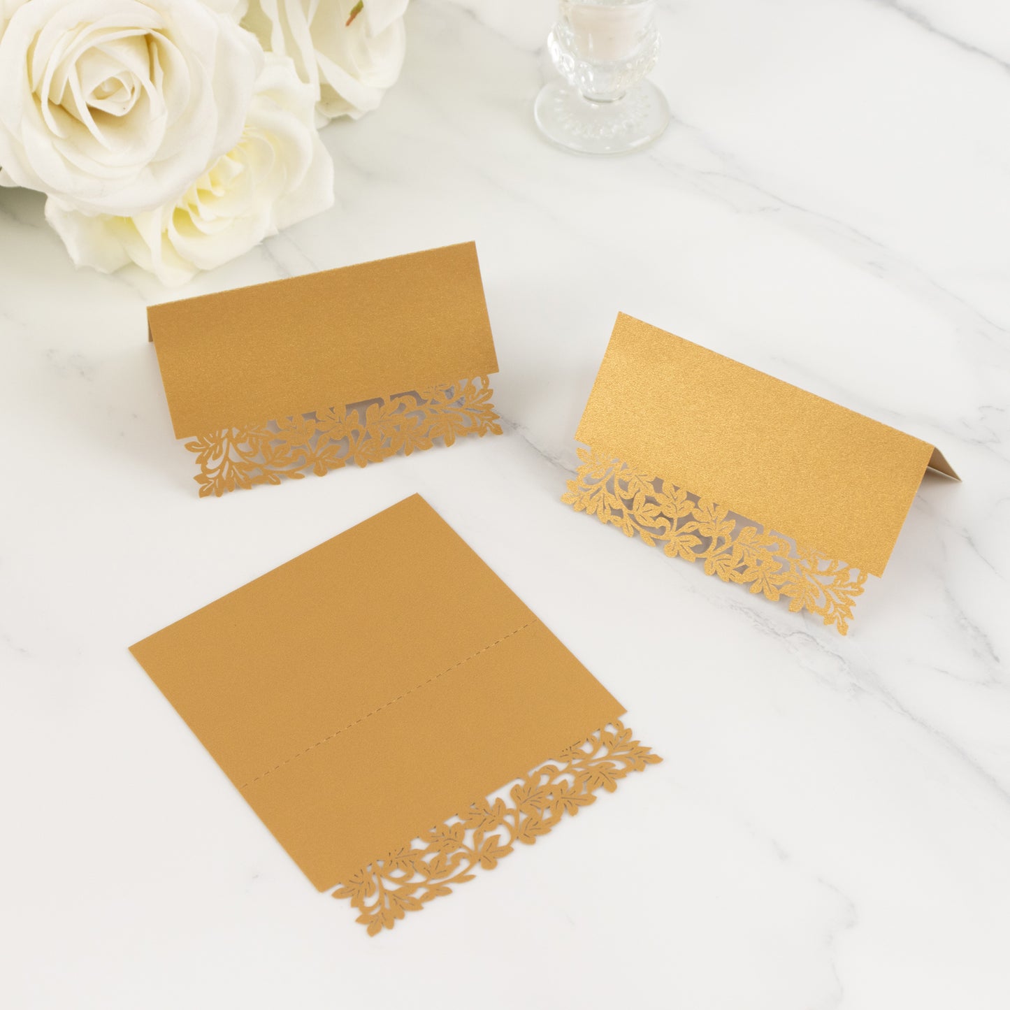 Gold wedding table number cards with laser cut leaf vine design.