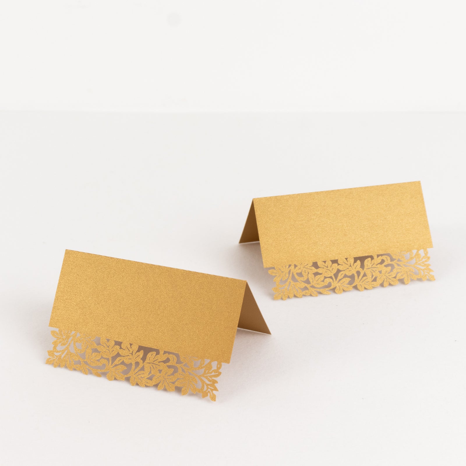 Gold wedding table number cards with laser cut leaf vine design.