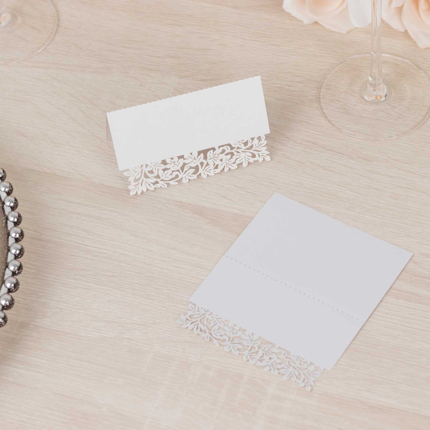White wedding table number cards with laser cut leaf vine design.