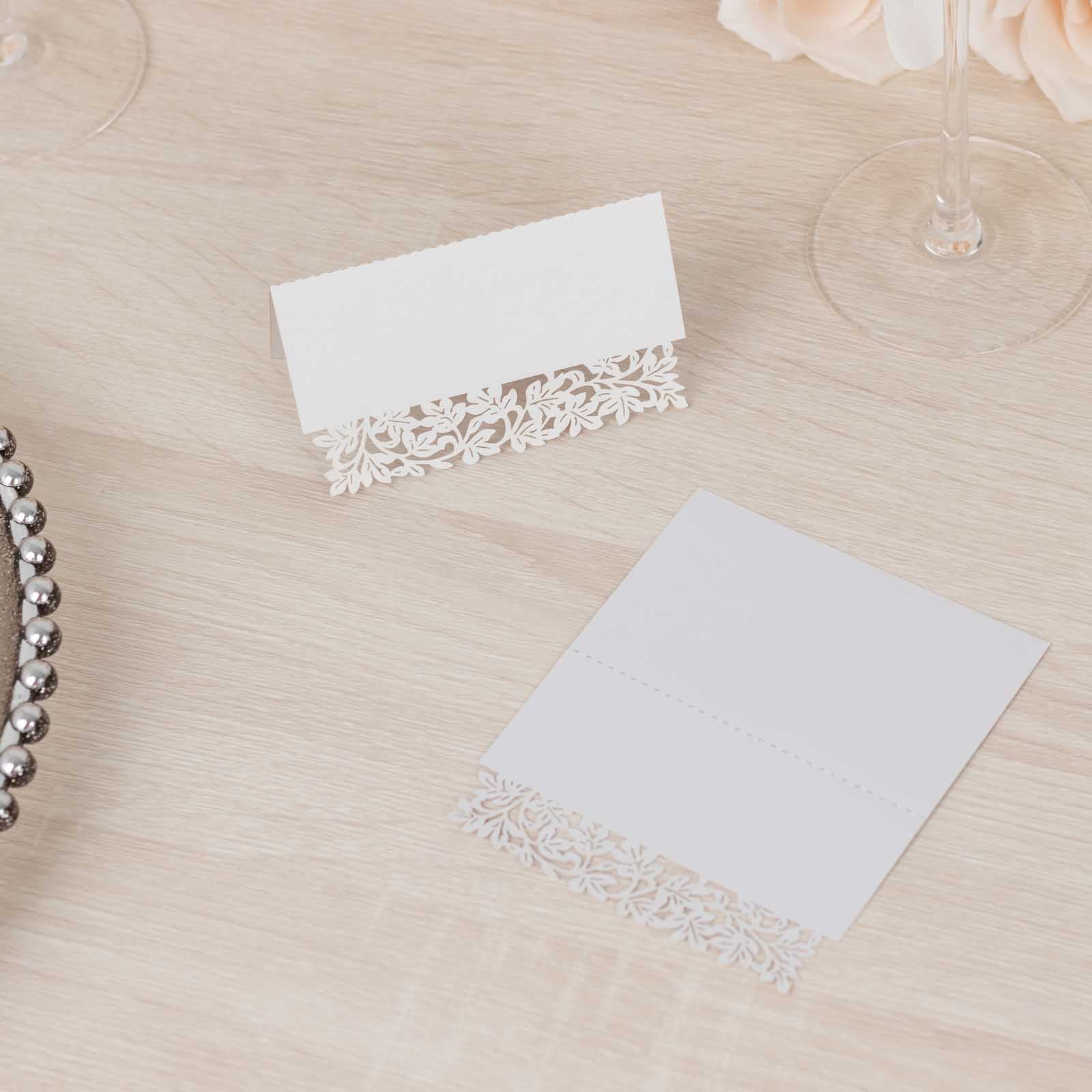 White wedding table number cards with laser cut leaf vine design.