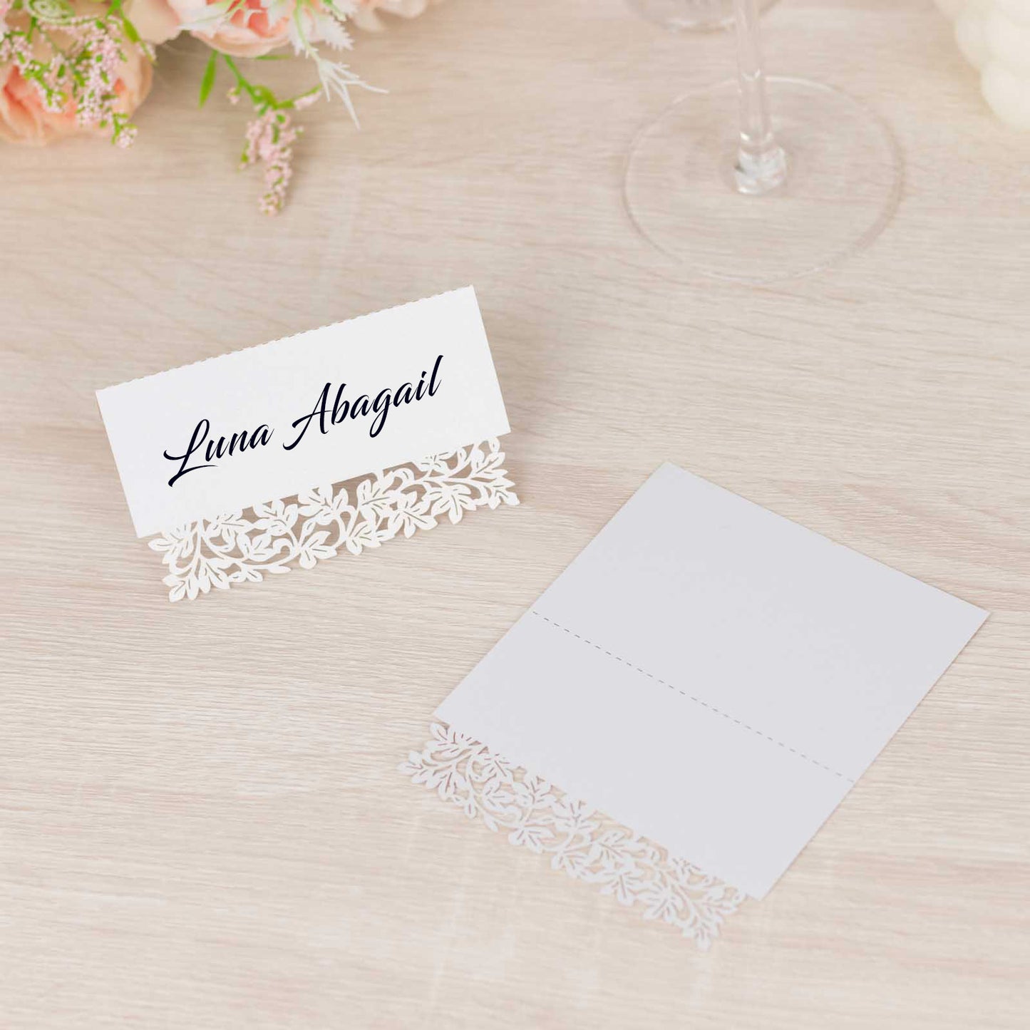 White wedding table number cards with laser cut leaf vine design.