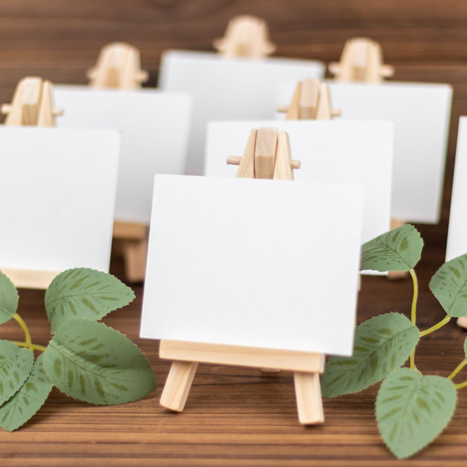 Natural mini rustic wooden easel stands with blank cards and greenery.
