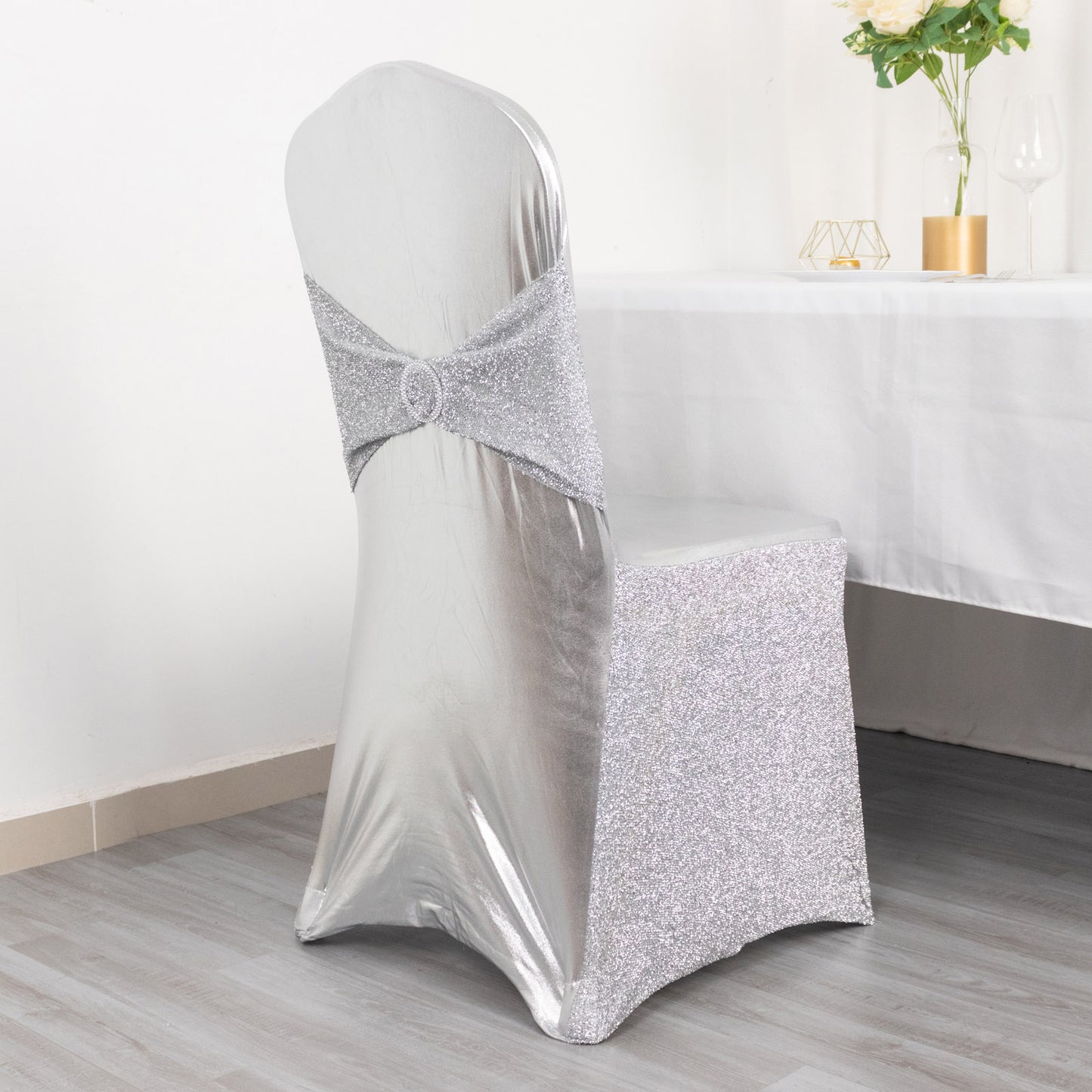 Metallic silver shimmer tinsel spandex chair cover with attached sash.