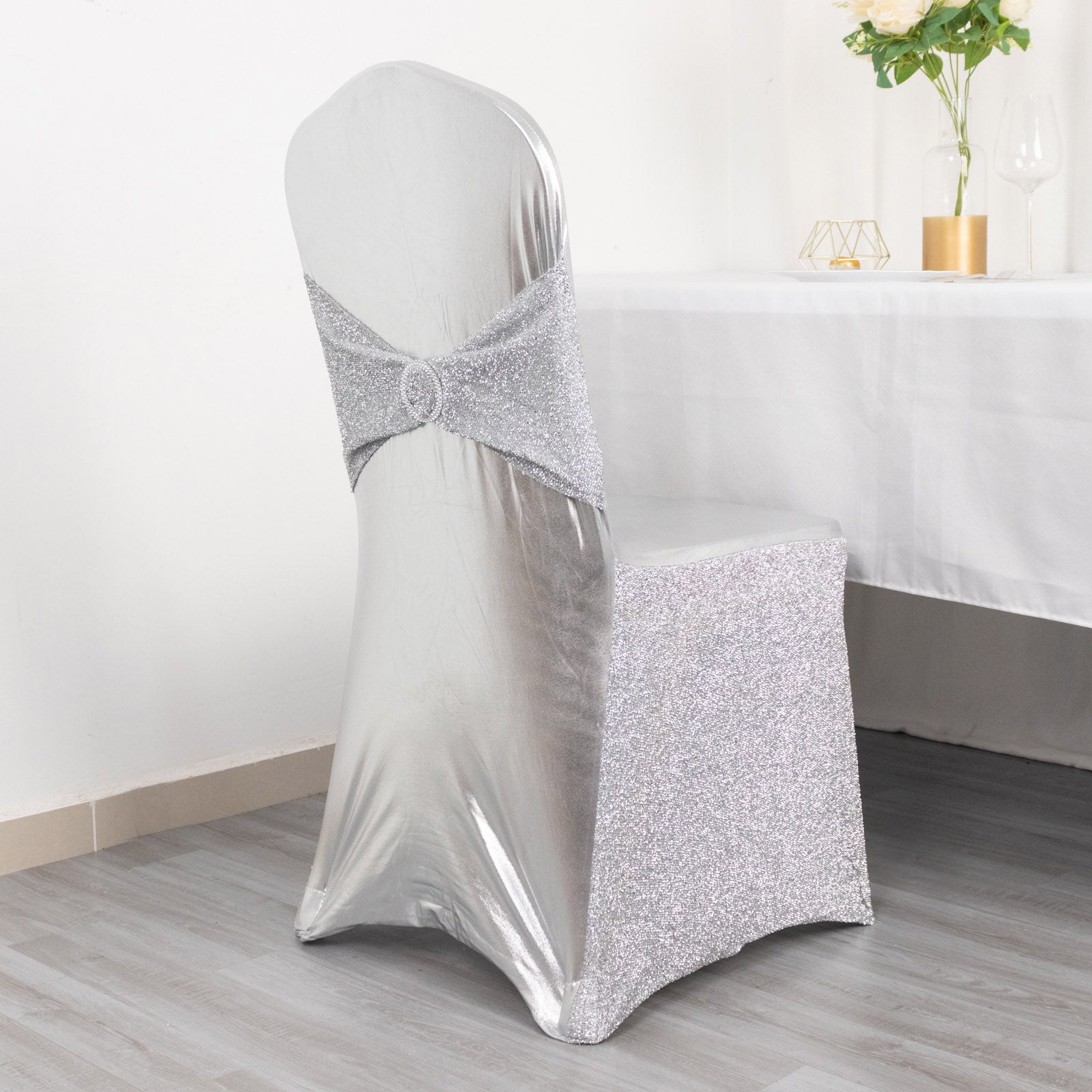 Metallic silver shimmer tinsel spandex chair cover with attached sash.