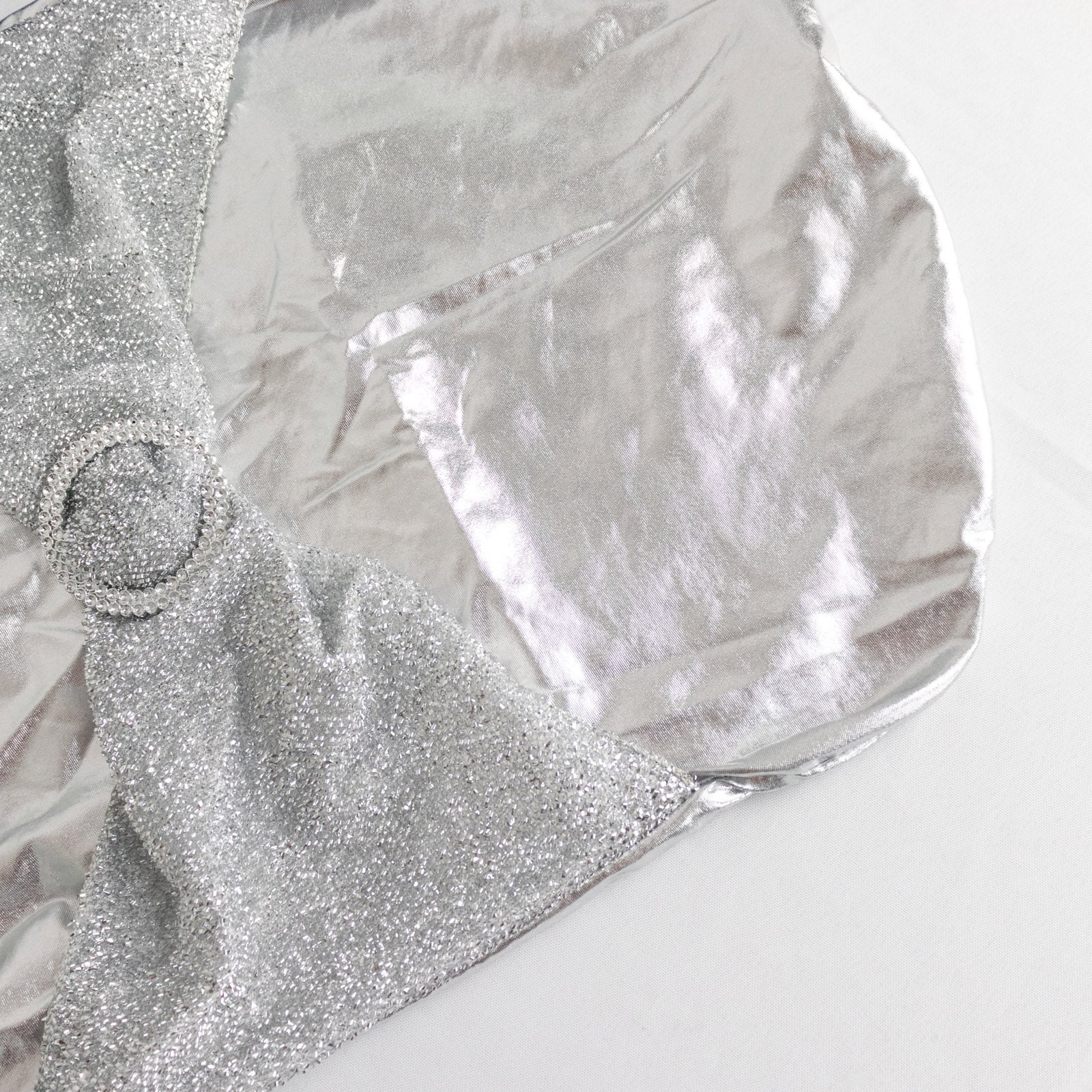 Metallic silver shimmer tinsel spandex chair cover with attached sash and rhinestone buckle.