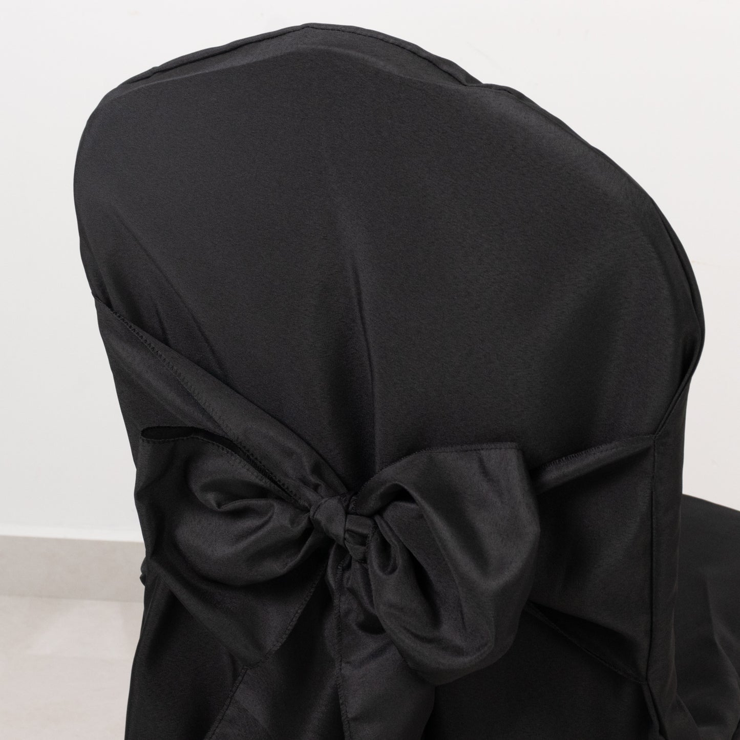 Black banquet chair cover with attached sash, reusable and stain-resistant.