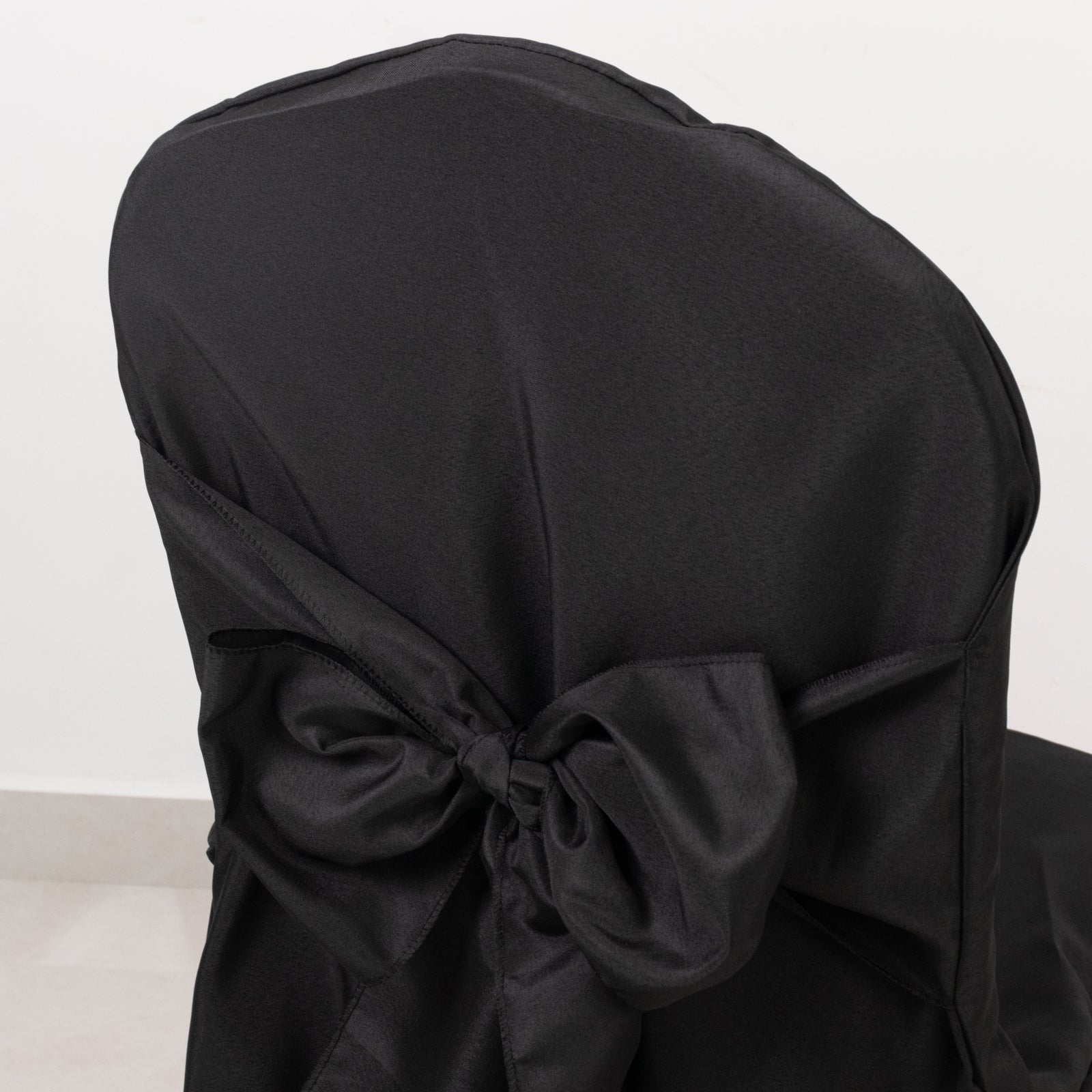Black banquet chair cover with attached sash, reusable and stain-resistant.