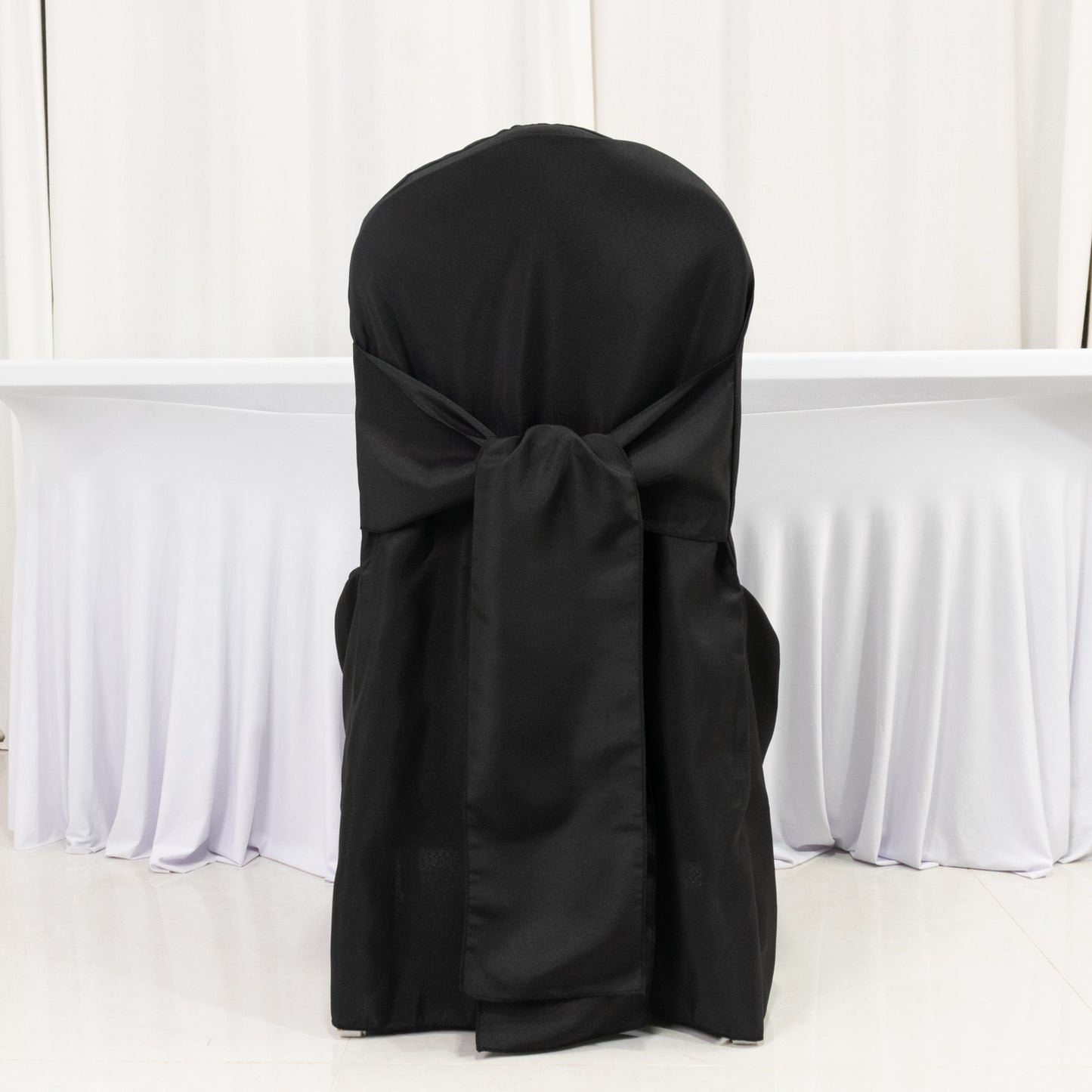 Black polyester slip-on banquet chair cover with attached sash.