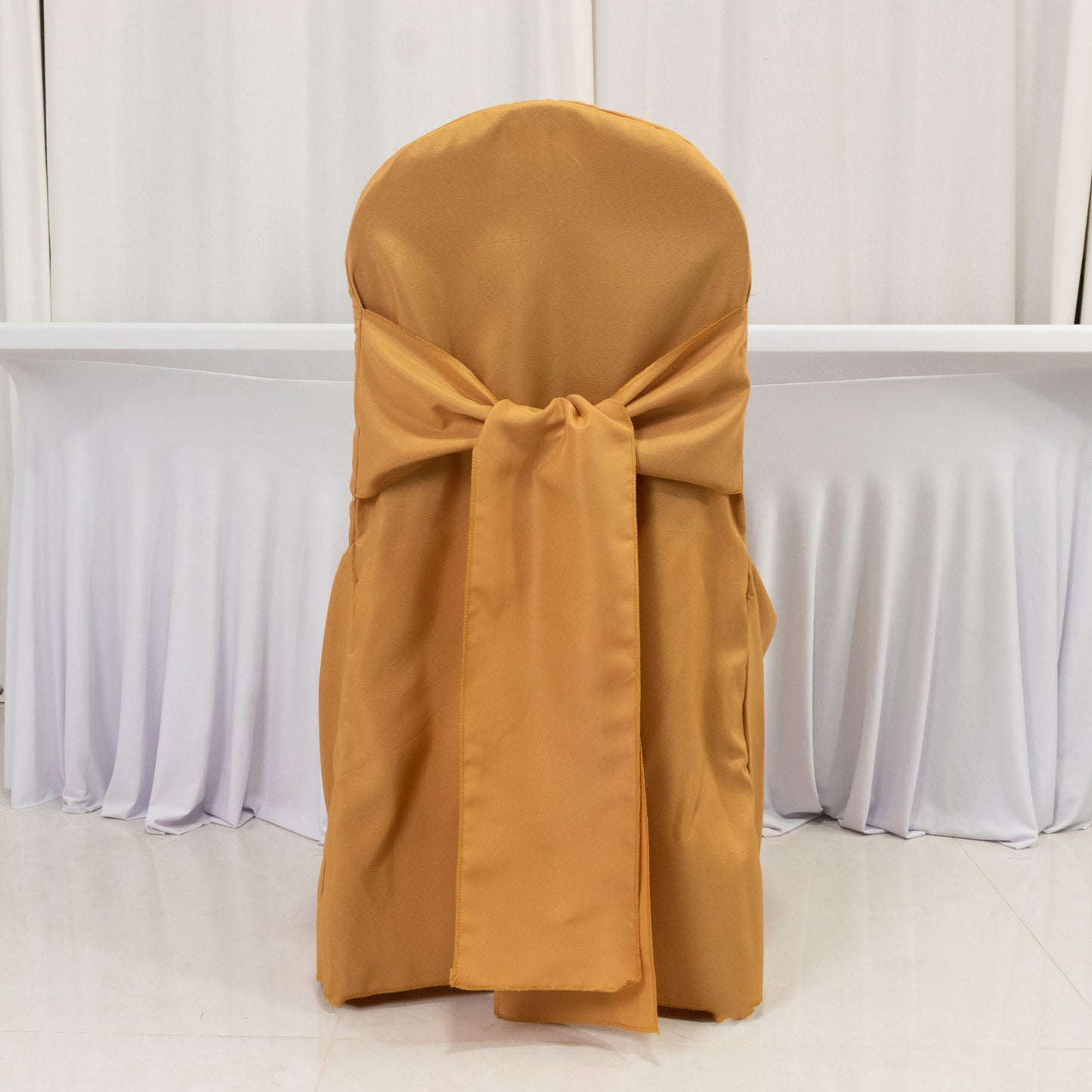 Gold banquet chair cover with attached sash, reusable and stain-resistant.