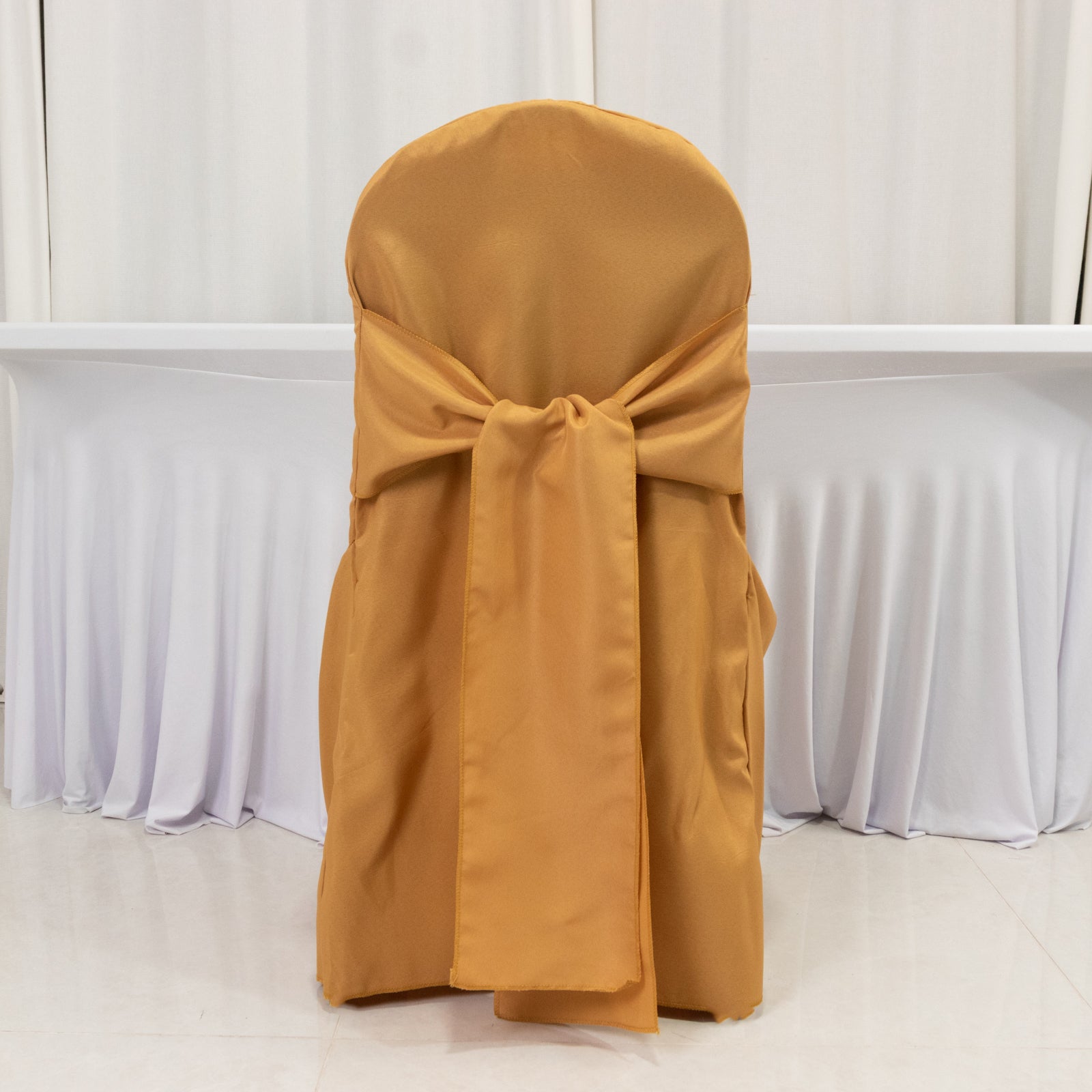 Gold banquet chair cover with attached sash, reusable and stain-resistant.