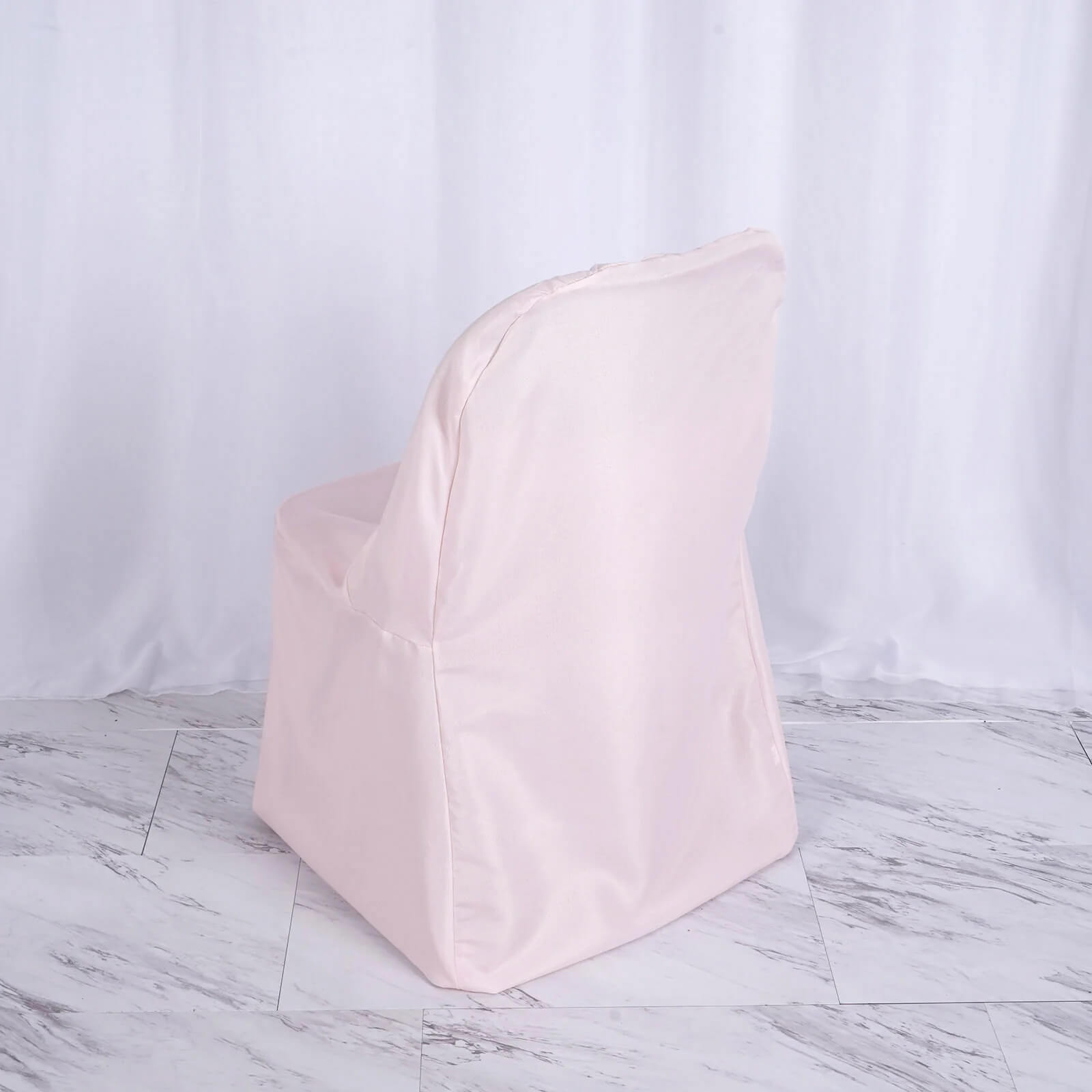 Blush polyester folding chair cover on a chair.