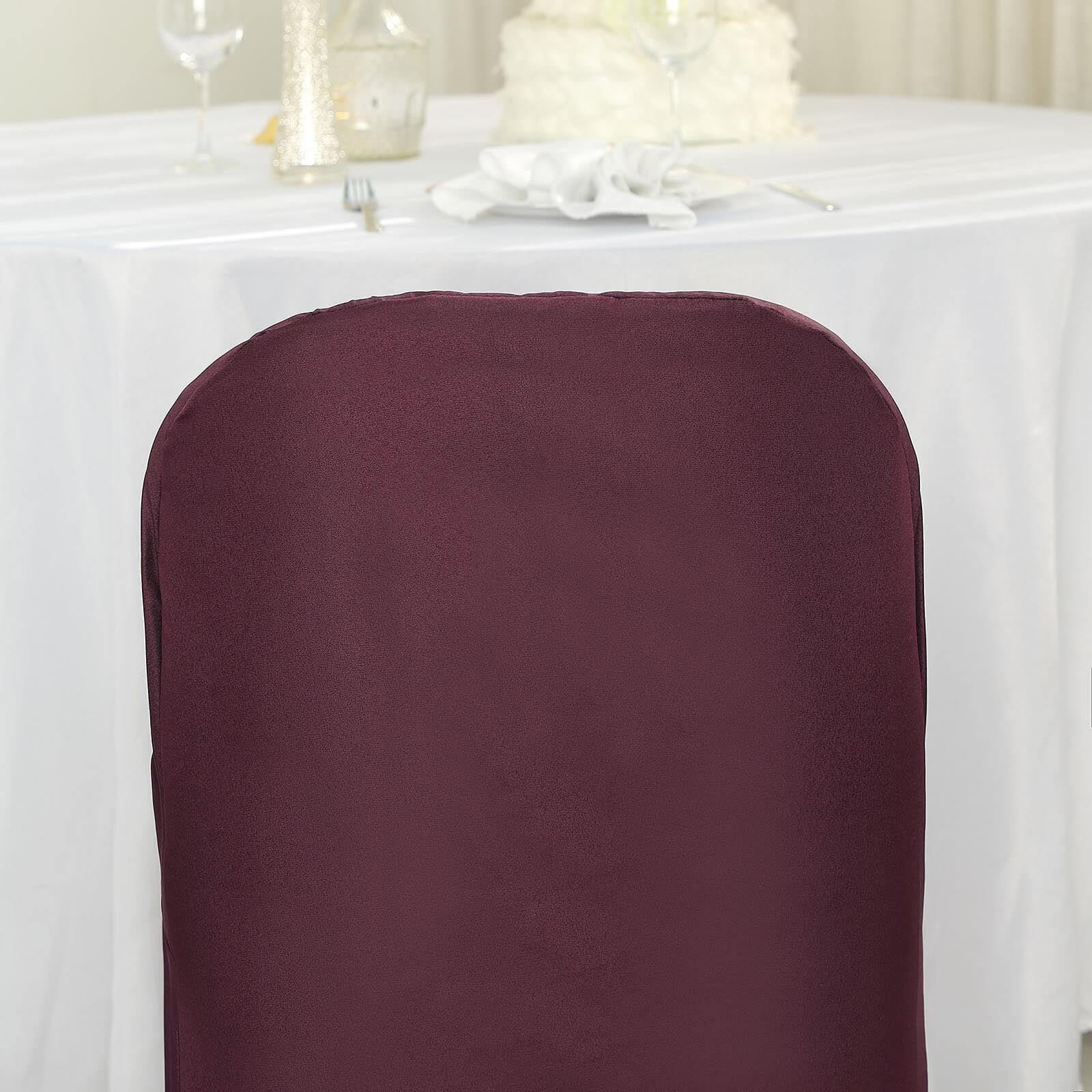 Burgundy folding chair cover on a white table setting.