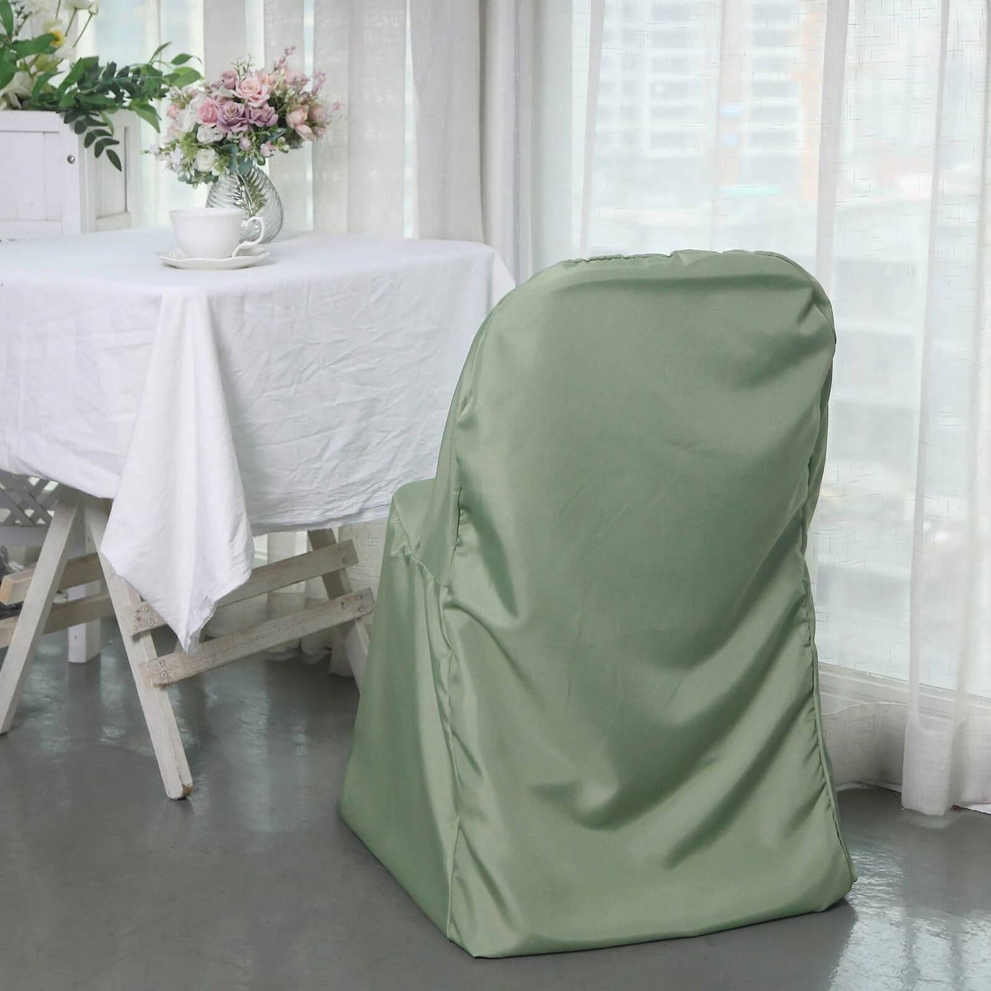 Dusty sage green polyester folding chair cover on a chair.